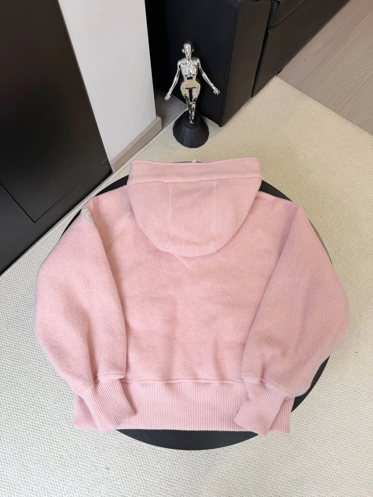 大鹅/Canada Goose抓绒羊毛饰章连帽夹克外套 面料选择: 以羊毛为主体，加入极少量氨纶和聚酯纤维混纺而成的羊毛抓绒面料。羊毛作为核心天然成分，提供无与伦比的温度调节、抑菌防臭和亲肤感。少量氨纶的喂入赋予了面料一定的四向弹性，日常活动时毫无束缚感。作为抓绒结构的基础，聚酯纤维增强了面料的耐久性、抗皱性和快干性，它构成了抓绒的蓬松感，并提供锁住空气等功能。 细节1: 衣袖和下摆采用2乘2罗纹收口，其强大的弹性，可以紧密贴合不同粗细的手腕和腰部，形成一个有效的&lsquo;密封&rsquo;,防止冷风倒灌。在多次拉伸和使用后仍能保持原有形状，不易松垮变形。且罗纹袖口能传递一种设计感，强化视觉美观度。 细节2: 兜帽设计与松紧扣的搭配提升穿戴时的保暖度与防风性能。 辅料:定制弹性抽绳松紧扣定制拉链吊坠定制臂章 尺码：S M L 颜色：黑 灰 咖 米 粉