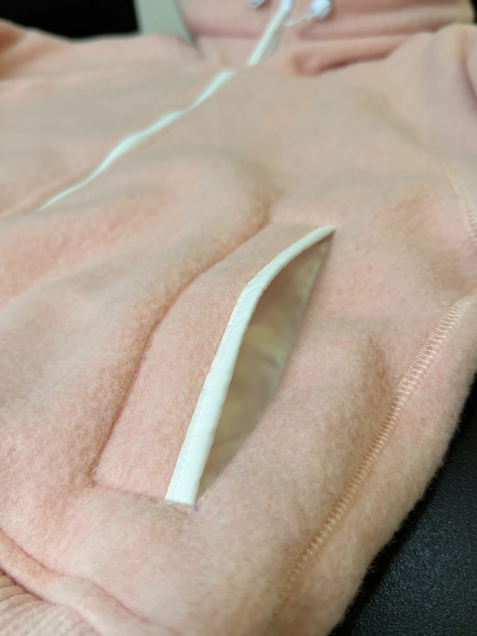 大鹅/Canada Goose抓绒羊毛饰章连帽夹克外套 面料选择: 以羊毛为主体，加入极少量氨纶和聚酯纤维混纺而成的羊毛抓绒面料。羊毛作为核心天然成分，提供无与伦比的温度调节、抑菌防臭和亲肤感。少量氨纶的喂入赋予了面料一定的四向弹性，日常活动时毫无束缚感。作为抓绒结构的基础，聚酯纤维增强了面料的耐久性、抗皱性和快干性，它构成了抓绒的蓬松感，并提供锁住空气等功能。 细节1: 衣袖和下摆采用2乘2罗纹收口，其强大的弹性，可以紧密贴合不同粗细的手腕和腰部，形成一个有效的&lsquo;密封&rsquo;,防止冷风倒灌。在多次拉伸和使用后仍能保持原有形状，不易松垮变形。且罗纹袖口能传递一种设计感，强化视觉美观度。 细节2: 兜帽设计与松紧扣的搭配提升穿戴时的保暖度与防风性能。 辅料:定制弹性抽绳松紧扣定制拉链吊坠定制臂章 尺码：S M L 颜色：黑 灰 咖 米 粉