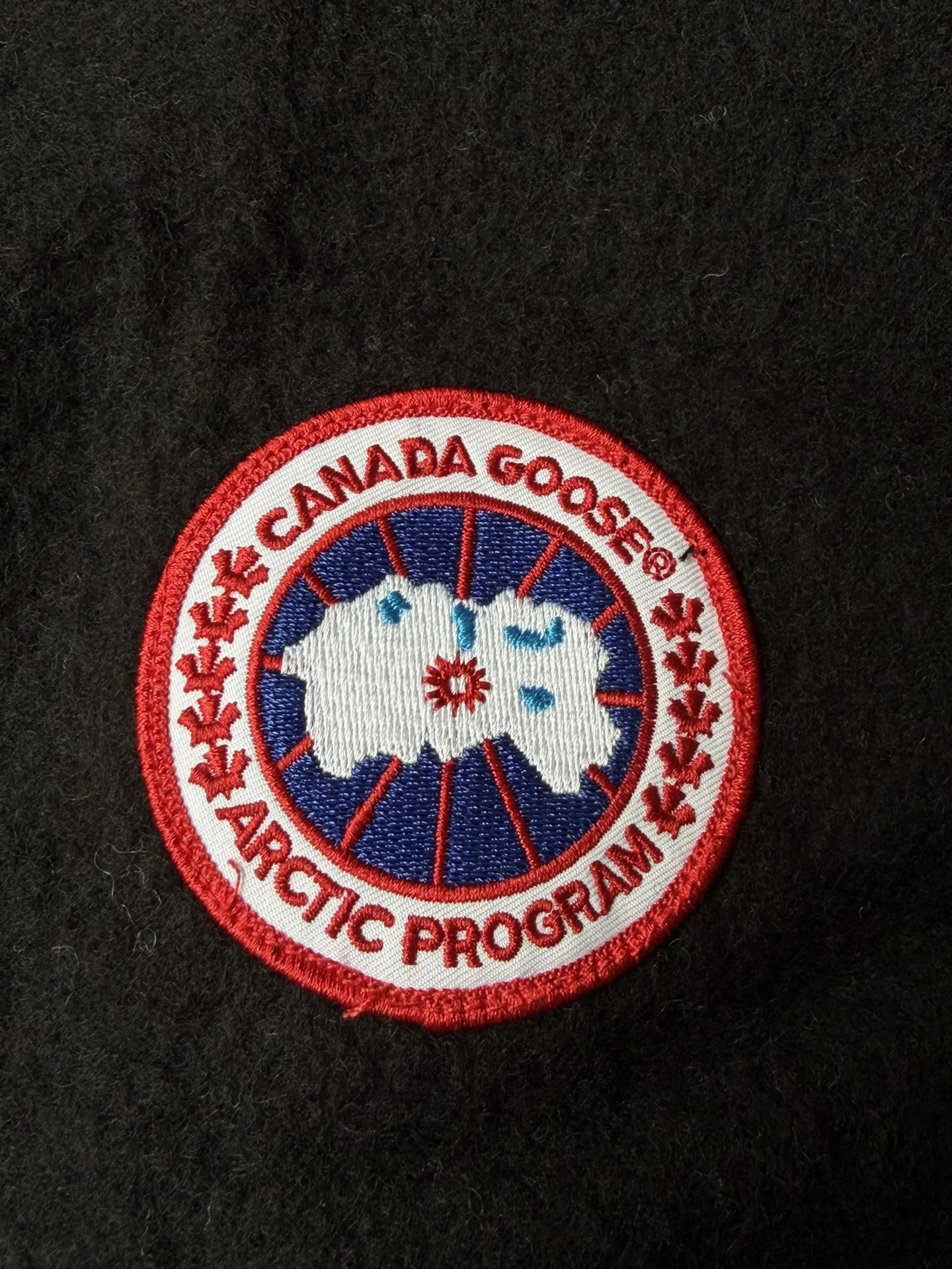 大鹅/Canada Goose抓绒羊毛饰章连帽夹克外套 面料选择: 以羊毛为主体，加入极少量氨纶和聚酯纤维混纺而成的羊毛抓绒面料。羊毛作为核心天然成分，提供无与伦比的温度调节、抑菌防臭和亲肤感。少量氨纶的喂入赋予了面料一定的四向弹性，日常活动时毫无束缚感。作为抓绒结构的基础，聚酯纤维增强了面料的耐久性、抗皱性和快干性，它构成了抓绒的蓬松感，并提供锁住空气等功能。 细节1: 衣袖和下摆采用2乘2罗纹收口，其强大的弹性，可以紧密贴合不同粗细的手腕和腰部，形成一个有效的&lsquo;密封&rsquo;,防止冷风倒灌。在多次拉伸和使用后仍能保持原有形状，不易松垮变形。且罗纹袖口能传递一种设计感，强化视觉美观度。 细节2: 兜帽设计与松紧扣的搭配提升穿戴时的保暖度与防风性能。 辅料:定制弹性抽绳松紧扣定制拉链吊坠定制臂章 尺码：S M L 颜色：黑 灰 咖 米 粉