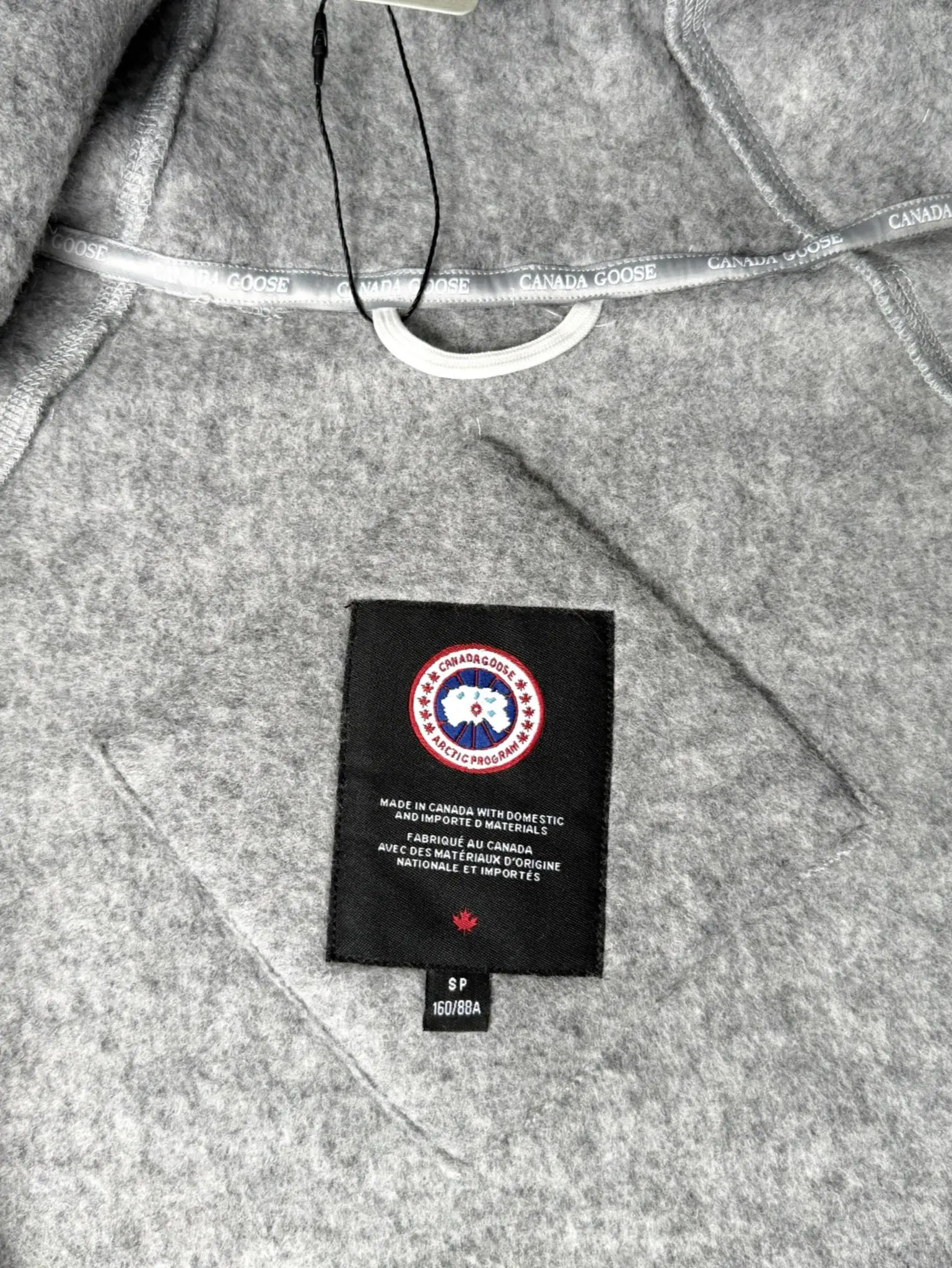 大鹅/Canada Goose抓绒羊毛饰章连帽夹克外套 面料选择: 以羊毛为主体,加入极少量氨纶和聚酯纤维混纺而成的羊毛抓绒面料。羊毛作为核心天然成分,提供无与伦比的温度调节、抑菌防臭和亲肤感。少量氨纶的喂入赋予了面料一定的四向弹性,日常活动时毫无束缚感。作为抓绒结构的基础,聚酯纤维增强了面料的耐久性、抗皱性和快干性,它构成了抓绒的蓬松感,并提供锁住空气等功能。 细节1: 衣袖和下摆采用2乘2罗纹收口,其强大的弹性,可以紧密贴合不同粗细的手腕和腰部,形成一个有效的‘密封’,防止冷风倒灌。在多次拉伸和使用后仍能保持原有形状,不易松垮变形。且罗纹袖口能传递一种设计感,强化视觉美观度。 细节2: 兜帽设计与松紧扣的搭配提升穿戴时的保暖度与防风性能。 辅料:定制弹性抽绳松紧扣定制拉链吊坠定制臂章 尺码:S M L 颜色:黑 灰 咖 米 粉