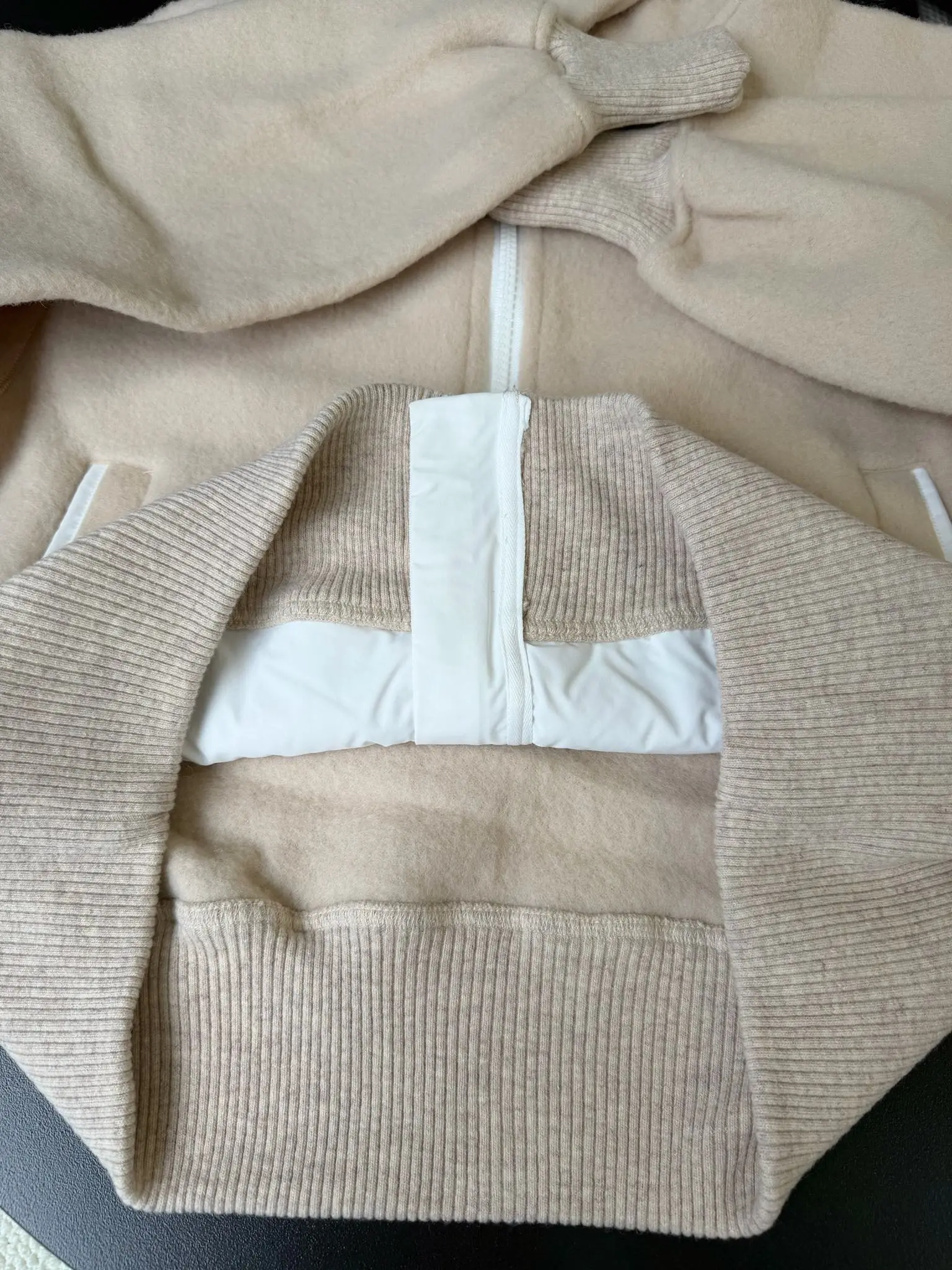 大鹅/Canada Goose抓绒羊毛饰章连帽夹克外套 面料选择: 以羊毛为主体，加入极少量氨纶和聚酯纤维混纺而成的羊毛抓绒面料。羊毛作为核心天然成分，提供无与伦比的温度调节、抑菌防臭和亲肤感。少量氨纶的喂入赋予了面料一定的四向弹性，日常活动时毫无束缚感。作为抓绒结构的基础，聚酯纤维增强了面料的耐久性、抗皱性和快干性，它构成了抓绒的蓬松感，并提供锁住空气等功能。 细节1: 衣袖和下摆采用2乘2罗纹收口，其强大的弹性，可以紧密贴合不同粗细的手腕和腰部，形成一个有效的&lsquo;密封&rsquo;,防止冷风倒灌。在多次拉伸和使用后仍能保持原有形状，不易松垮变形。且罗纹袖口能传递一种设计感，强化视觉美观度。 细节2: 兜帽设计与松紧扣的搭配提升穿戴时的保暖度与防风性能。 辅料:定制弹性抽绳松紧扣定制拉链吊坠定制臂章 尺码：S M L 颜色：黑 灰 咖 米 粉