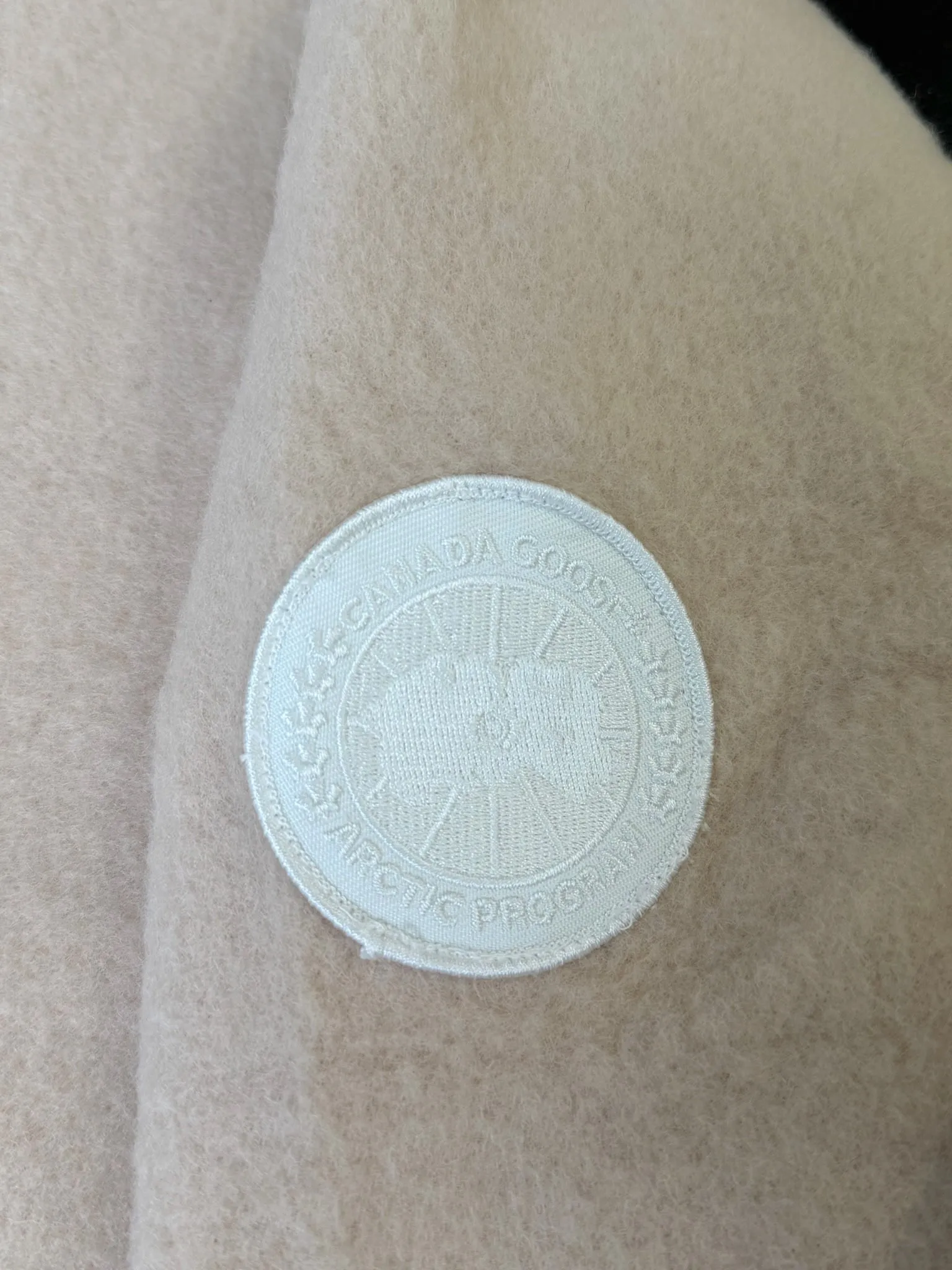 大鹅/Canada Goose抓绒羊毛饰章连帽夹克外套 面料选择: 以羊毛为主体，加入极少量氨纶和聚酯纤维混纺而成的羊毛抓绒面料。羊毛作为核心天然成分，提供无与伦比的温度调节、抑菌防臭和亲肤感。少量氨纶的喂入赋予了面料一定的四向弹性，日常活动时毫无束缚感。作为抓绒结构的基础，聚酯纤维增强了面料的耐久性、抗皱性和快干性，它构成了抓绒的蓬松感，并提供锁住空气等功能。 细节1: 衣袖和下摆采用2乘2罗纹收口，其强大的弹性，可以紧密贴合不同粗细的手腕和腰部，形成一个有效的&lsquo;密封&rsquo;,防止冷风倒灌。在多次拉伸和使用后仍能保持原有形状，不易松垮变形。且罗纹袖口能传递一种设计感，强化视觉美观度。 细节2: 兜帽设计与松紧扣的搭配提升穿戴时的保暖度与防风性能。 辅料:定制弹性抽绳松紧扣定制拉链吊坠定制臂章 尺码：S M L 颜色：黑 灰 咖 米 粉