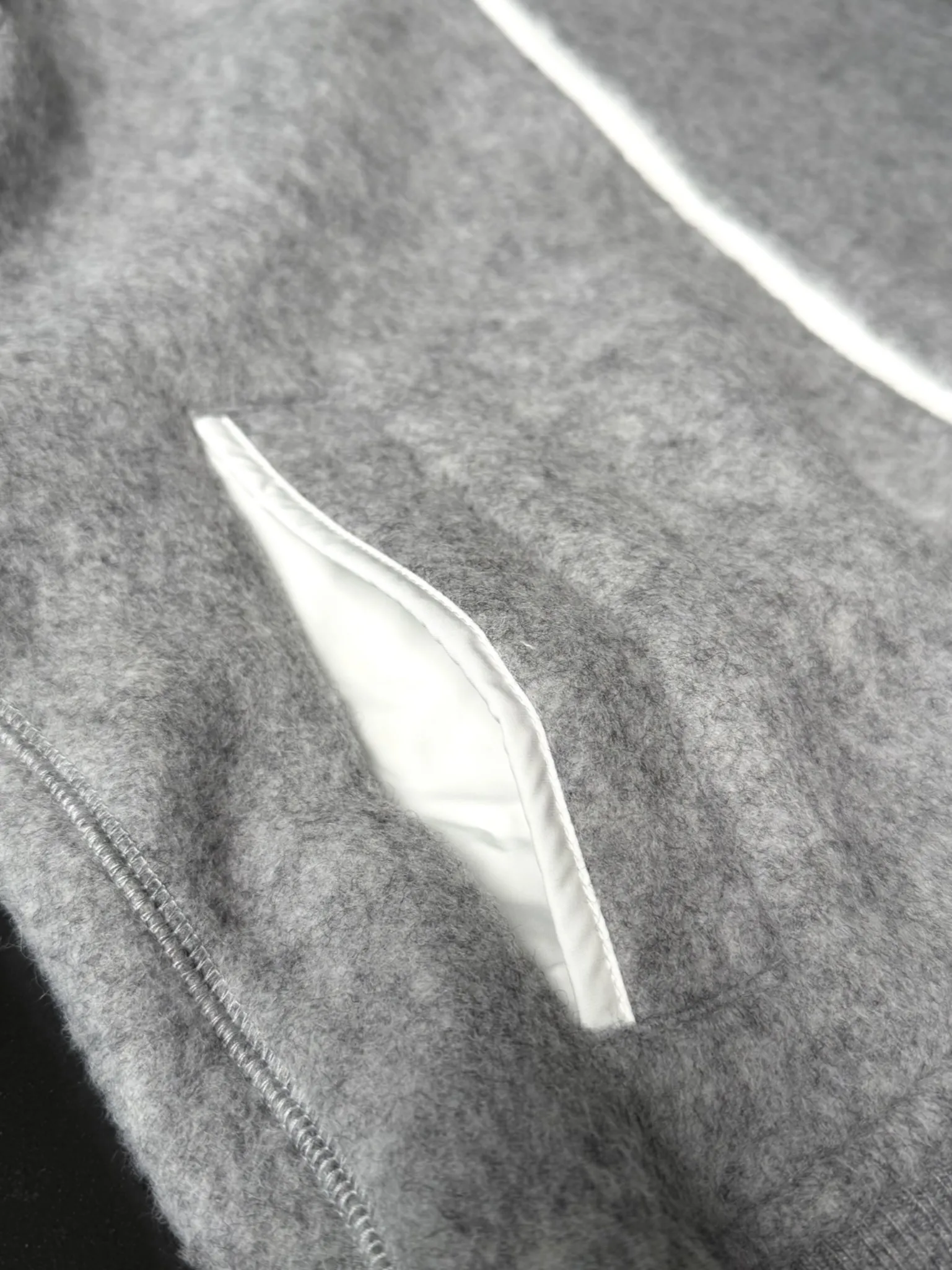 大鹅/Canada Goose抓绒羊毛饰章连帽夹克外套 面料选择: 以羊毛为主体，加入极少量氨纶和聚酯纤维混纺而成的羊毛抓绒面料。羊毛作为核心天然成分，提供无与伦比的温度调节、抑菌防臭和亲肤感。少量氨纶的喂入赋予了面料一定的四向弹性，日常活动时毫无束缚感。作为抓绒结构的基础，聚酯纤维增强了面料的耐久性、抗皱性和快干性，它构成了抓绒的蓬松感，并提供锁住空气等功能。 细节1: 衣袖和下摆采用2乘2罗纹收口，其强大的弹性，可以紧密贴合不同粗细的手腕和腰部，形成一个有效的&lsquo;密封&rsquo;,防止冷风倒灌。在多次拉伸和使用后仍能保持原有形状，不易松垮变形。且罗纹袖口能传递一种设计感，强化视觉美观度。 细节2: 兜帽设计与松紧扣的搭配提升穿戴时的保暖度与防风性能。 辅料:定制弹性抽绳松紧扣定制拉链吊坠定制臂章 尺码：S M L 颜色：黑 灰 咖 米 粉