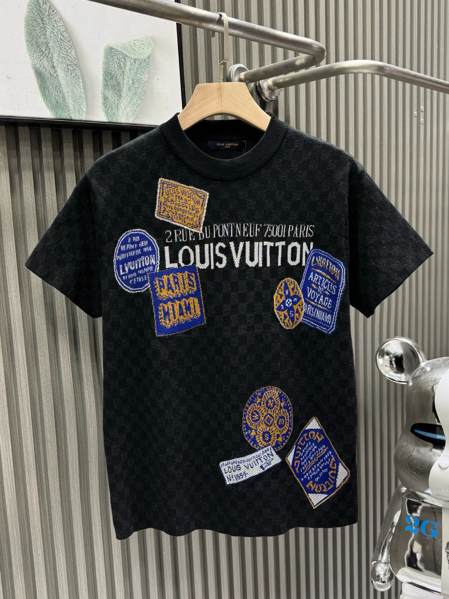 💰200🀄️ Louis Vuitton路易威登 LOUIS VUITTON 棋盘格标签针织短袖 采用定制棉质加光丝面料匠心制作 Damier提花嵌花织纹 德国进口挂毛机织片而成 织线原衣对色 环保固色定染 提花面料要求纱支精细衣身运用进口16针织令士提方格织法完美跟提花工艺每件耗时要150分钟 图案采取双面挂毛工艺 精细做工 肌理纹路清晰 极细织线由环保纤维打造 缝合采用的是16针盘 每个收口还要手工挑 缝线都要松紧一致要平顺 出品大身前后左右整齐对位理衣身面料具有软糯垂坠触感 面料舒适柔软 亲肤透气 富有弹性 全衣以棋盘格底纹 胸前品牌字母刺绣 配蓝色徽章设计感十足 和袖子均有品牌 细节做工精致 整体走线平直细腻 面料舒适柔软 颜色一致无色差 能与同款搭配营造时尚造型 三标齐全 男女同款