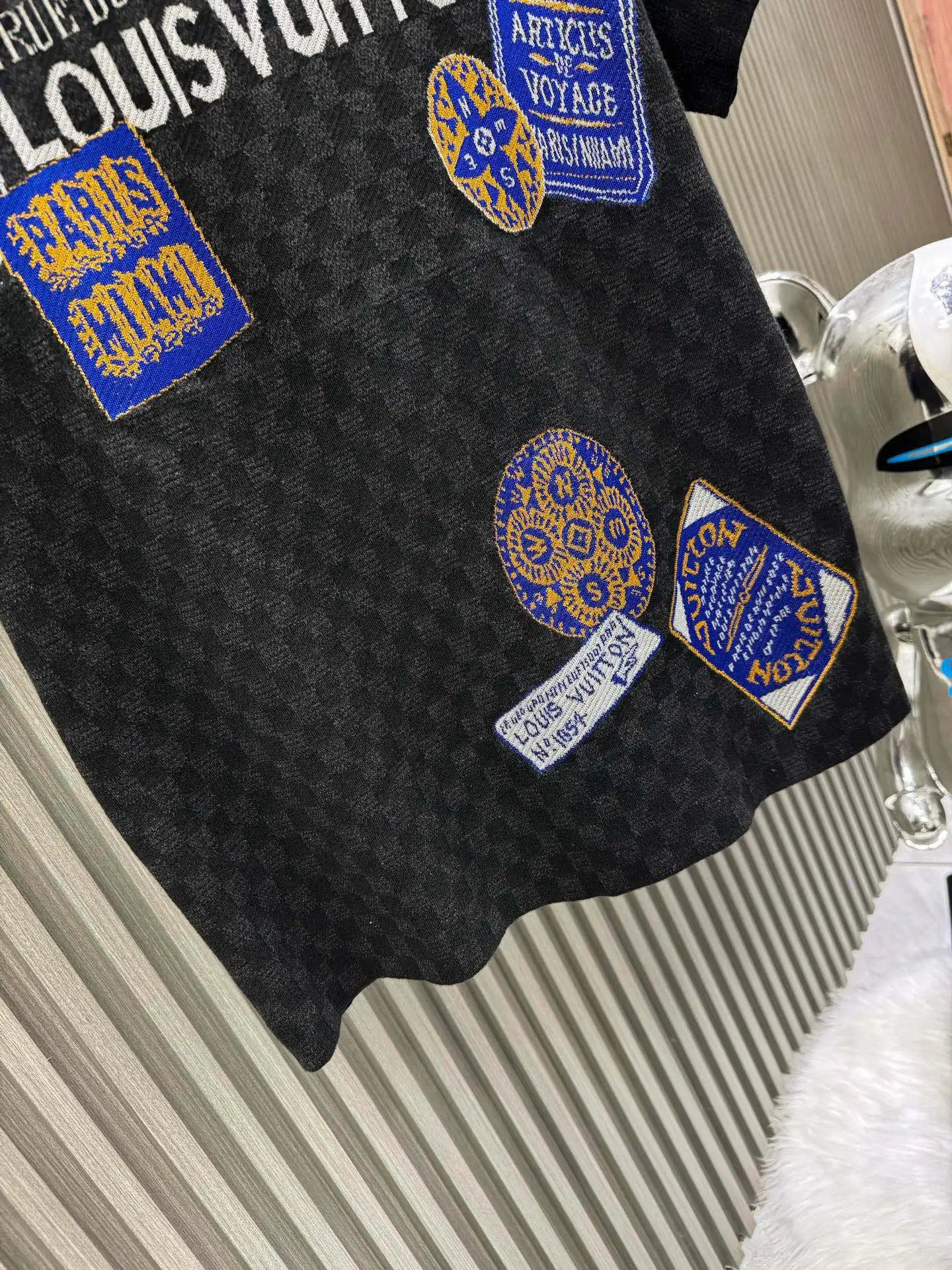 💰200🀄️ Louis Vuitton路易威登 LOUIS VUITTON 棋盘格标签针织短袖 采用定制棉质加光丝面料匠心制作 Damier提花嵌花织纹 德国进口挂毛机织片而成 织线原衣对色 环保固色定染 提花面料要求纱支精细衣身运用进口16针织令士提方格织法完美跟提花工艺每件耗时要150分钟 图案采取双面挂毛工艺 精细做工 肌理纹路清晰 极细织线由环保纤维打造 缝合采用的是16针盘 每个收口还要手工挑 缝线都要松紧一致要平顺 出品大身前后左右整齐对位理衣身面料具有软糯垂坠触感 面料舒适柔软 亲肤透气 富有弹性 全衣以棋盘格底纹 胸前品牌字母刺绣 配蓝色徽章设计感十足 和袖子均有品牌 细节做工精致 整体走线平直细腻 面料舒适柔软 颜色一致无色差 能与同款搭配营造时尚造型 三标齐全 男女同款