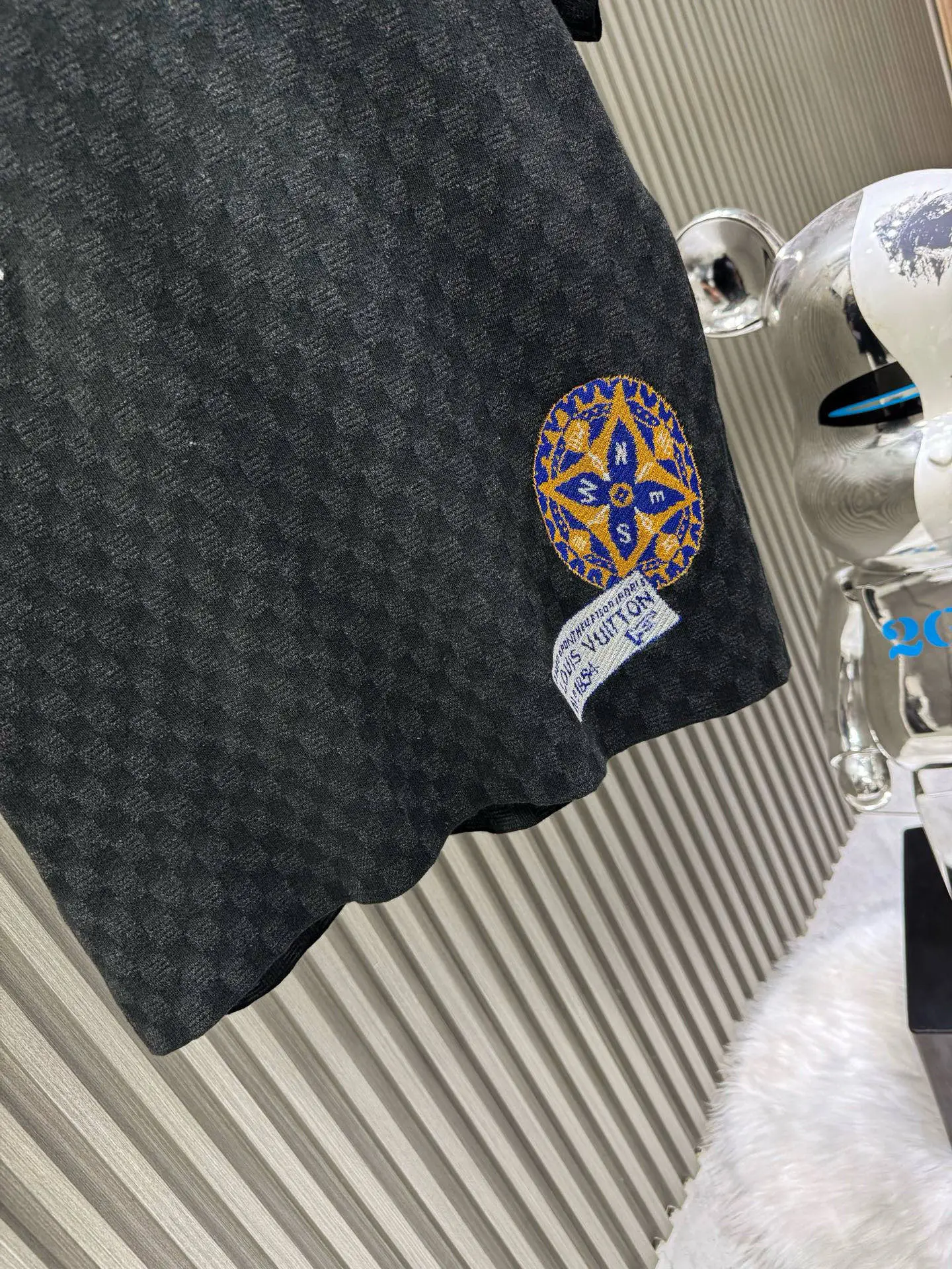 💰200🀄️ Louis Vuitton路易威登 LOUIS VUITTON 棋盘格标签针织短袖 采用定制棉质加光丝面料匠心制作 Damier提花嵌花织纹 德国进口挂毛机织片而成 织线原衣对色 环保固色定染 提花面料要求纱支精细衣身运用进口16针织令士提方格织法完美跟提花工艺每件耗时要150分钟 图案采取双面挂毛工艺 精细做工 肌理纹路清晰 极细织线由环保纤维打造 缝合采用的是16针盘 每个收口还要手工挑 缝线都要松紧一致要平顺 出品大身前后左右整齐对位理衣身面料具有软糯垂坠触感 面料舒适柔软 亲肤透气 富有弹性 全衣以棋盘格底纹 胸前品牌字母刺绣 配蓝色徽章设计感十足 和袖子均有品牌 细节做工精致 整体走线平直细腻 面料舒适柔软 颜色一致无色差 能与同款搭配营造时尚造型 三标齐全 男女同款
