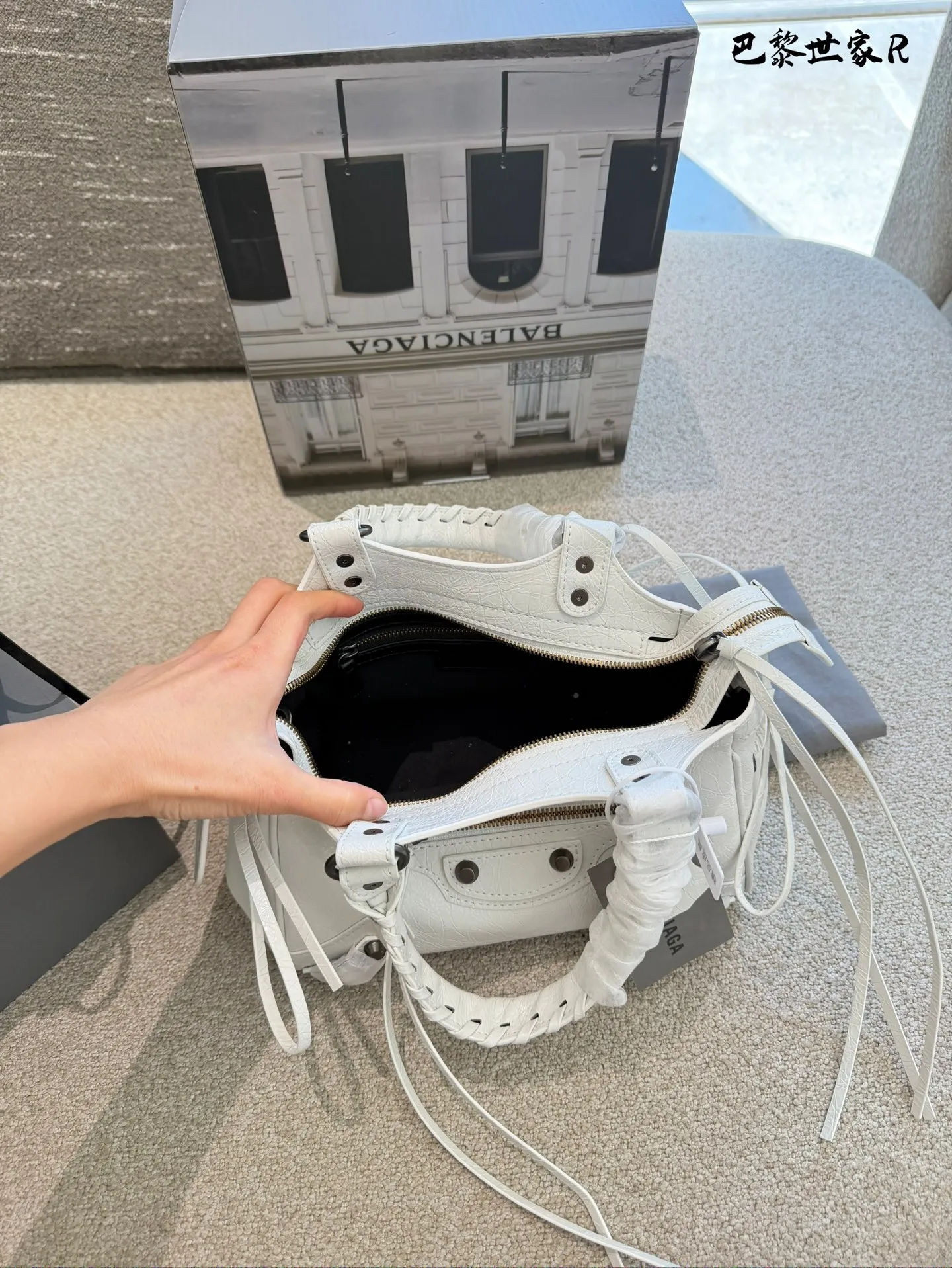 巴黎世家机车包p250 这是巴黎世家机车包,属于时尚界的经典单品。包身采用油蜡皮材质,配有铆钉装饰,设计硬朗且富有质感。常见尺寸有mini、小号和中号,适合不同身高和需求的人 群。原产地为法国,是巴黎世家品牌的标志性产品之一- ,深受全球时尚爱好者的喜爱。 养护方面,建议避免长时间暴露在阳光下,以免褪色。使用后及时清理表面灰尘,可用柔软布料轻轻擦拭。定期检查五金件是否松动,必要时可联系专业维修服务进行维护23cm