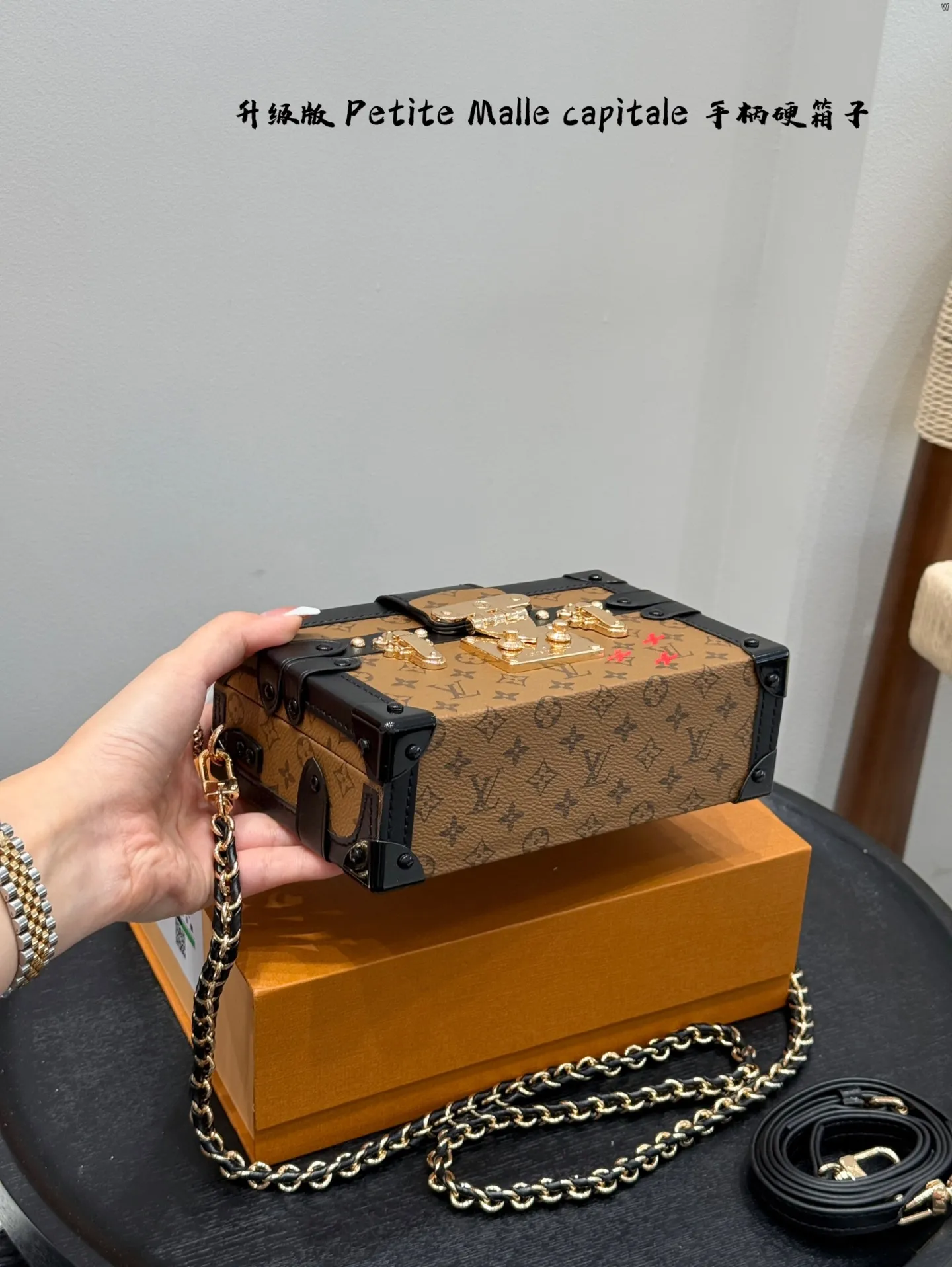 p185 礼盒包装 升级版! size:19*12cm Lv 秀款Petite Malle capitale手提手柄盒子新款 手提硬箱 跟以往的小箱子设计外形一样,新款只是增加手提把手, 缓缓流露复古气息。 既时尚又实用,它是一款多功能包,轻巧易用,允许多种携带方式:手拎、肩扛和斜挎。