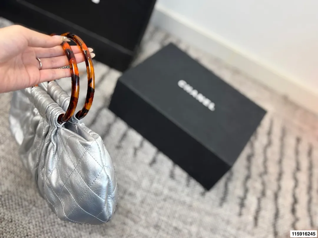 p145 配折叠盒 Chanel 26C玳瑁手柄福袋包 Chanel 26C早春系列福袋包，黑色麂皮+玳瑁色手柄，复古优雅感满满十。经典菱格纹缝线+双CLogo，细节超精致，手机小物轻松收纳，麂皮柔软，秋冬搭配超有氛围感 。玳瑁手柄光泽感强，手提或复古风都很出彩，实用又时髦，是热门单品！ 尺寸 30.20