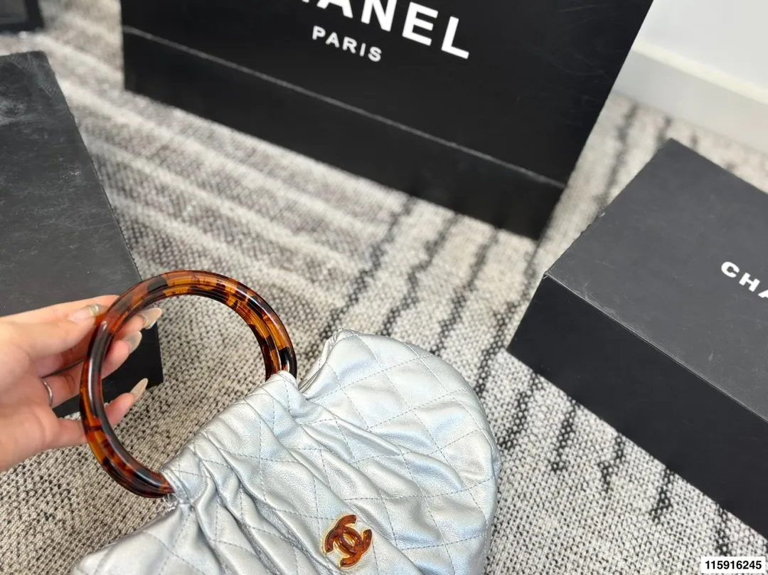 p145 配折叠盒 Chanel 26C玳瑁手柄福袋包 Chanel 26C早春系列福袋包,黑色麂皮+玳瑁色手柄,复古优雅感满满十。经典菱格纹缝线+双CLogo,细节超精致,手机小物轻松收纳,麂皮柔软,秋冬搭配超有氛围感 。玳瑁手柄光泽感强,手提或复古风都很出彩,实用又时髦,是热门单品! 尺寸 30.20