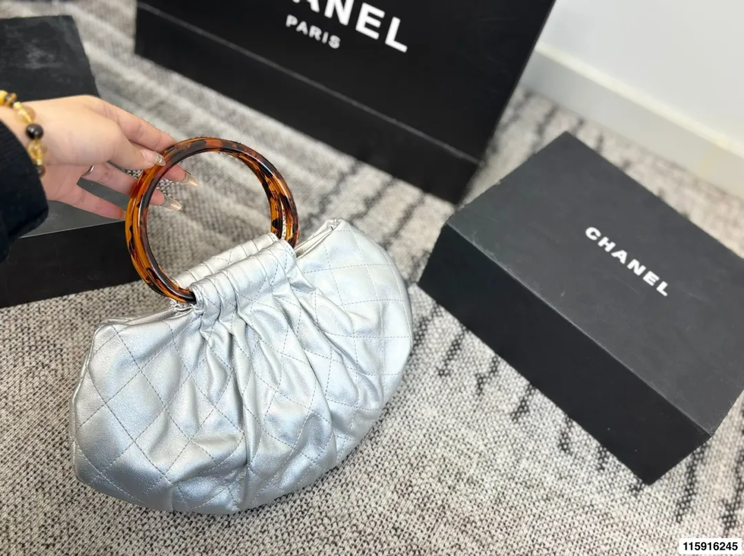 p145 配折叠盒 Chanel 26C玳瑁手柄福袋包 Chanel 26C早春系列福袋包，黑色麂皮+玳瑁色手柄，复古优雅感满满十。经典菱格纹缝线+双CLogo，细节超精致，手机小物轻松收纳，麂皮柔软，秋冬搭配超有氛围感 。玳瑁手柄光泽感强，手提或复古风都很出彩，实用又时髦，是热门单品！ 尺寸 30.20