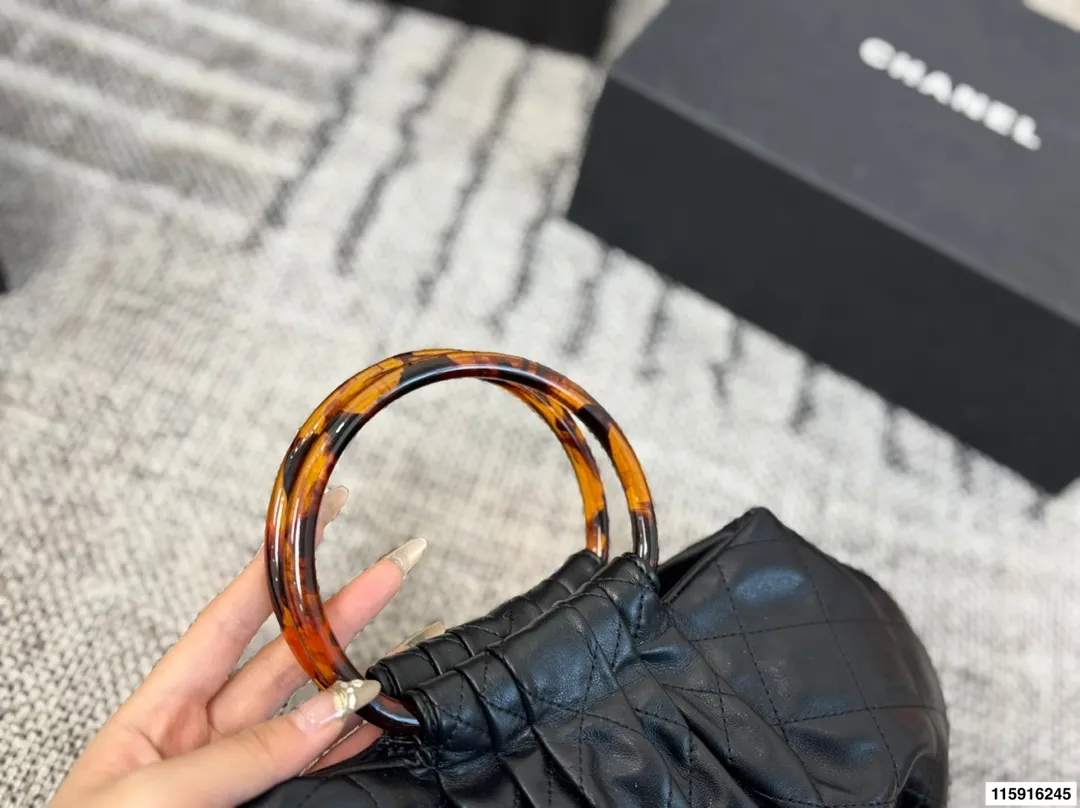 p145 配折叠盒 Chanel 26C玳瑁手柄福袋包 Chanel 26C早春系列福袋包,黑色麂皮+玳瑁色手柄,复古优雅感满满十。经典菱格纹缝线+双CLogo,细节超精致,手机小物轻松收纳,麂皮柔软,秋冬搭配超有氛围感 。玳瑁手柄光泽感强,手提或复古风都很出彩,实用又时髦,是热门单品! 尺寸 30.20