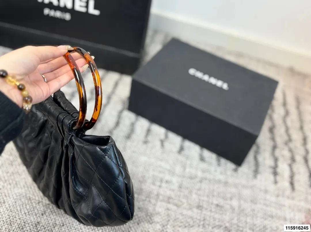 p145 配折叠盒 Chanel 26C玳瑁手柄福袋包 Chanel 26C早春系列福袋包,黑色麂皮+玳瑁色手柄,复古优雅感满满十。经典菱格纹缝线+双CLogo,细节超精致,手机小物轻松收纳,麂皮柔软,秋冬搭配超有氛围感 。玳瑁手柄光泽感强,手提或复古风都很出彩,实用又时髦,是热门单品! 尺寸 30.20