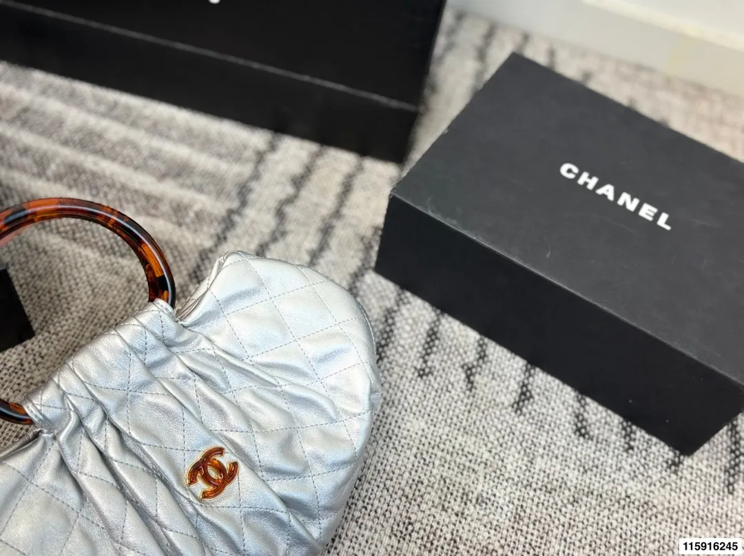 p145 配折叠盒 Chanel 26C玳瑁手柄福袋包 Chanel 26C早春系列福袋包，黑色麂皮+玳瑁色手柄，复古优雅感满满十。经典菱格纹缝线+双CLogo，细节超精致，手机小物轻松收纳，麂皮柔软，秋冬搭配超有氛围感 。玳瑁手柄光泽感强，手提或复古风都很出彩，实用又时髦，是热门单品！ 尺寸 30.20