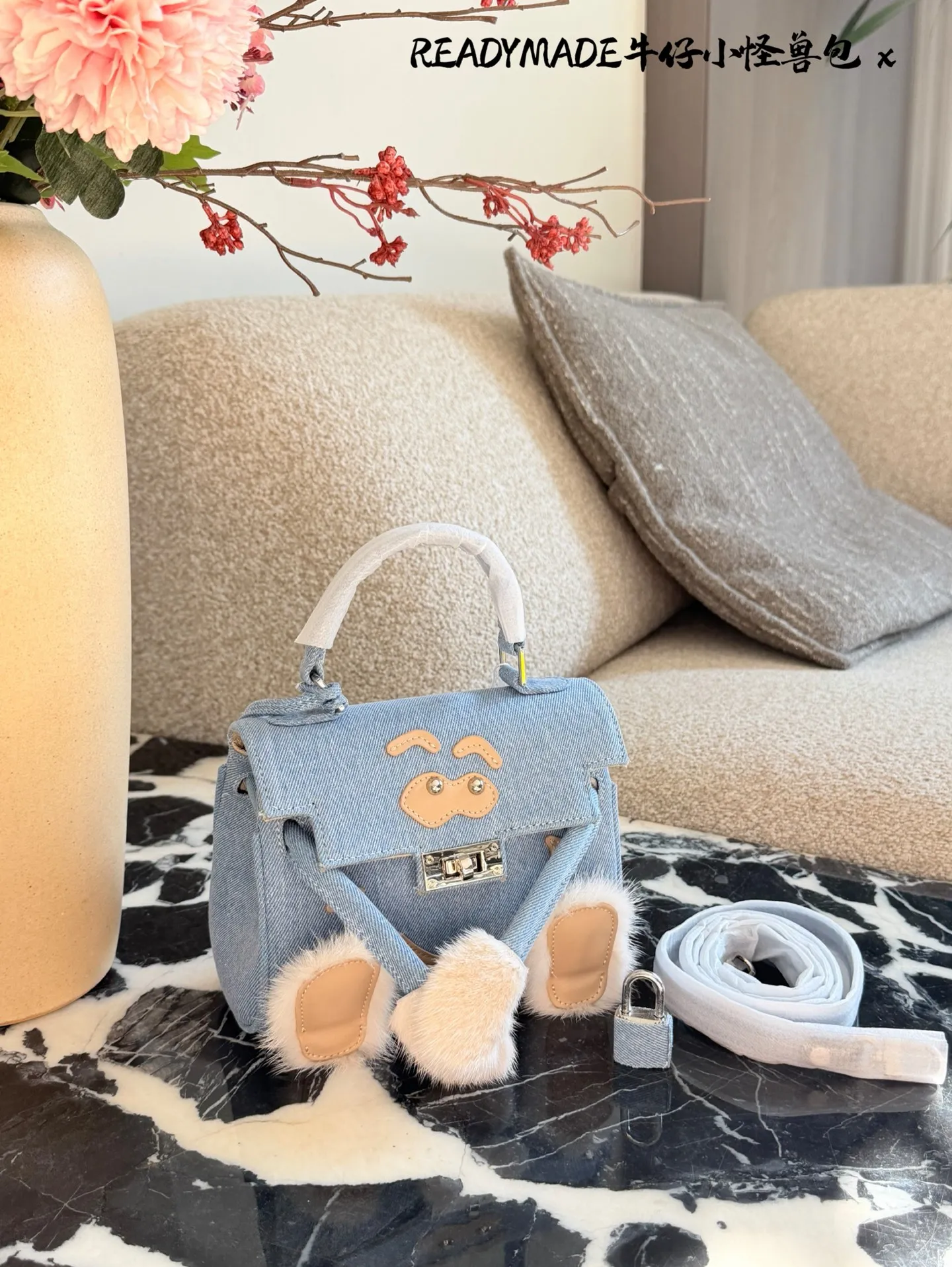 p215 READYMADE牛仔小怪兽包 国日本小众品牌READYMADE的牛仔小怪兽包,灵感来 自爱马仕Kelly Doll,浅蓝牛仔布+貂毛手脚,手感超柔软,趣味满分汁。迷你尺寸约18cm,能装手机、气垫等日常小物,手拎斜挎都OK,街头风、甜酷风都能轻松驾驭!部分配色已停产,收藏价值高,超适合喜欢个性和可爱风的姐妹们。