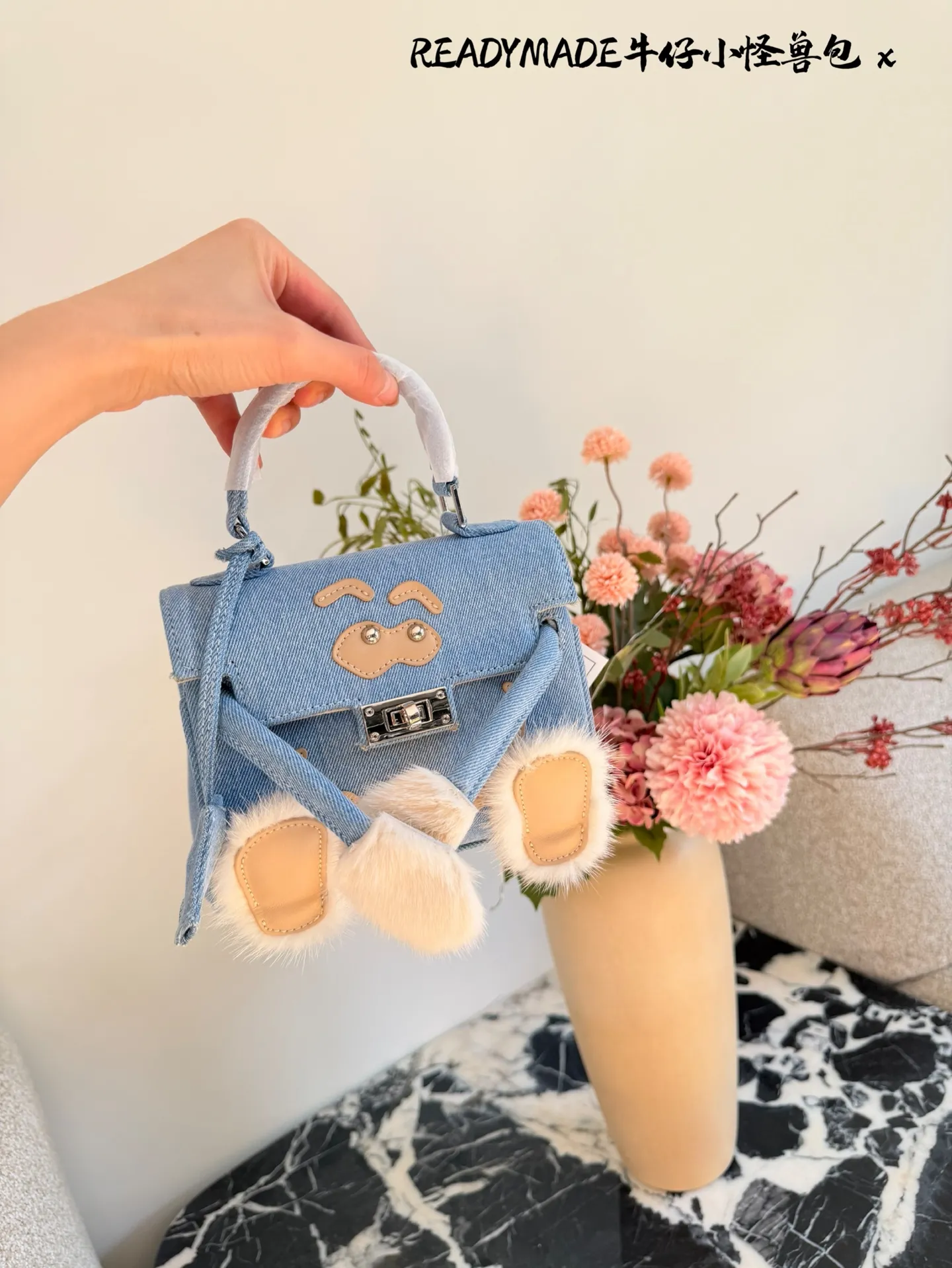 p215 READYMADE牛仔小怪兽包 国日本小众品牌READYMADE的牛仔小怪兽包,灵感来 自爱马仕Kelly Doll,浅蓝牛仔布+貂毛手脚,手感超柔软,趣味满分汁。迷你尺寸约18cm,能装手机、气垫等日常小物,手拎斜挎都OK,街头风、甜酷风都能轻松驾驭!部分配色已停产,收藏价值高,超适合喜欢个性和可爱风的姐妹们。
