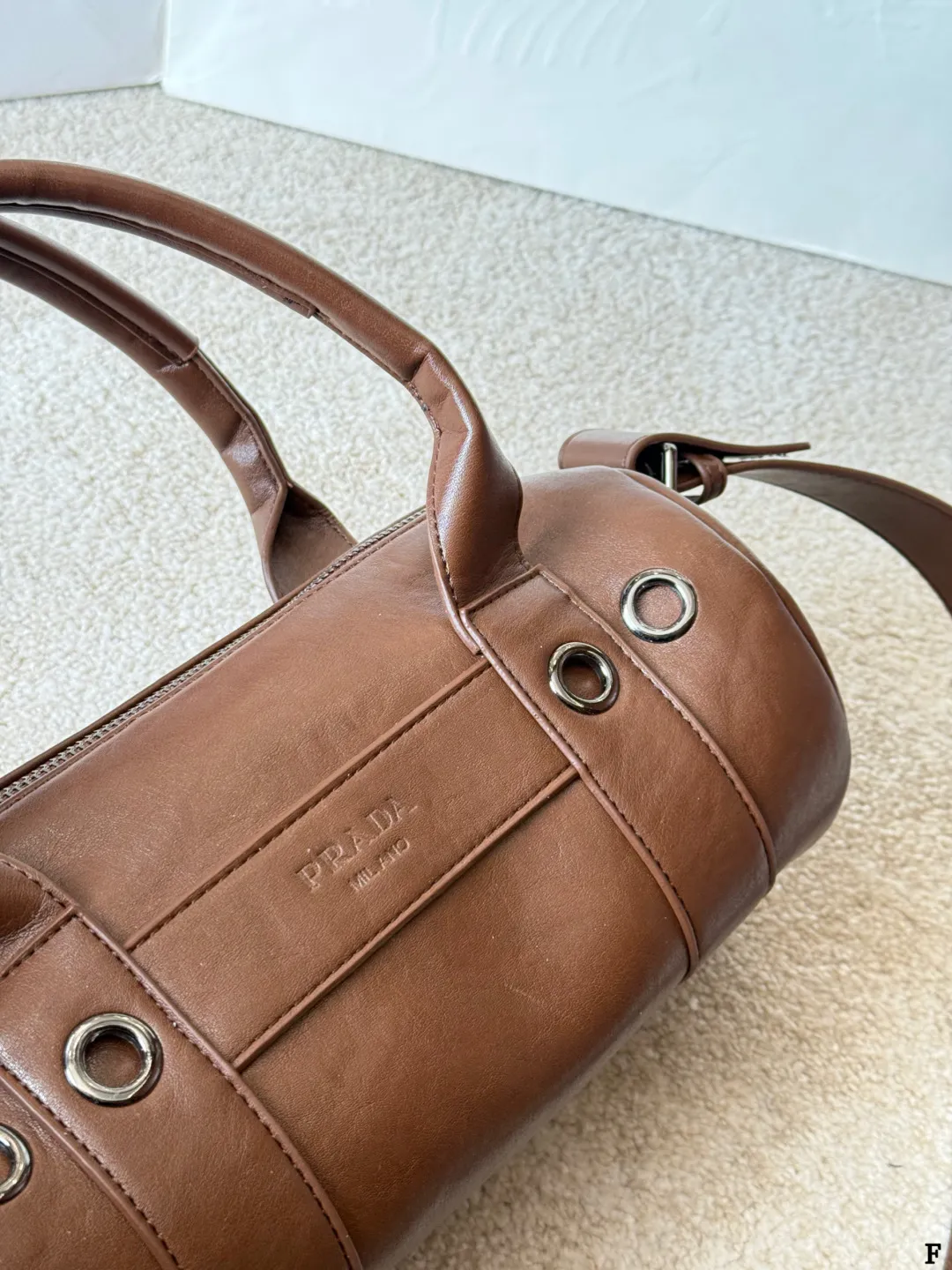 p170 Prada 26SS圆筒包 些Prada 26SS圆筒包是春夏系列新品,棕色皮革质感细腻耐用,简约复古风格超有范!圆筒造型+双提手+可拆卸肩带,手提斜挎都OK,通勤休闲都能搭。正面Logo低调有辨识度,金属环扣点缀细节满分。日本快闪首发,稀缺属性,时尚实用,Prada粉丝必入! 尺寸 30 15cm