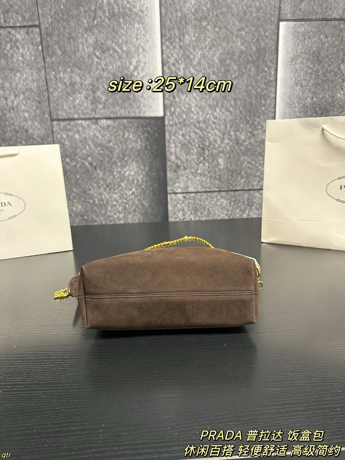 P105配盒 PRADA 普拉达 饭盒包 这款包采用进口麂皮，具有柔软的轮廓和多个口袋，轻质实用的Re-Nylon强调了设计的多功能风格，而皮革细节和标志性点缀则反映了Prada的手工传统，配有2条可拆卸、可调节的编织标志带肩带，容量空间大，上身效果非常时尚。又是一款永久不过时爆款。值得拥有 尺寸：25*14cm