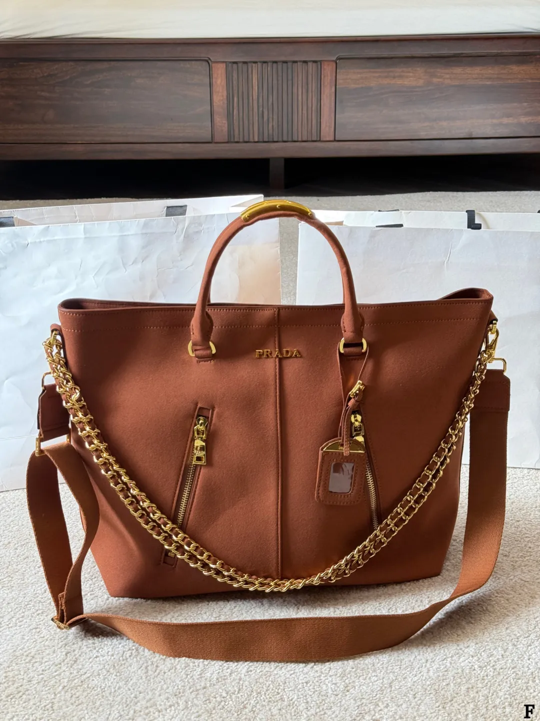 p190 Prada链条托特包 Prada这款棕色链条托特包,采用优质牛皮,手感细腻耐用。金属链条+皮革肩带,手提斜挎都OK,超百搭!正面Logo低调有辦识度,内部空间超大,通勤or短途旅行都能装下日常用品。拉链口袋设计,收纳更方便,实用又时髦,是都市女生的热门选择! 尺寸 35 33cm
