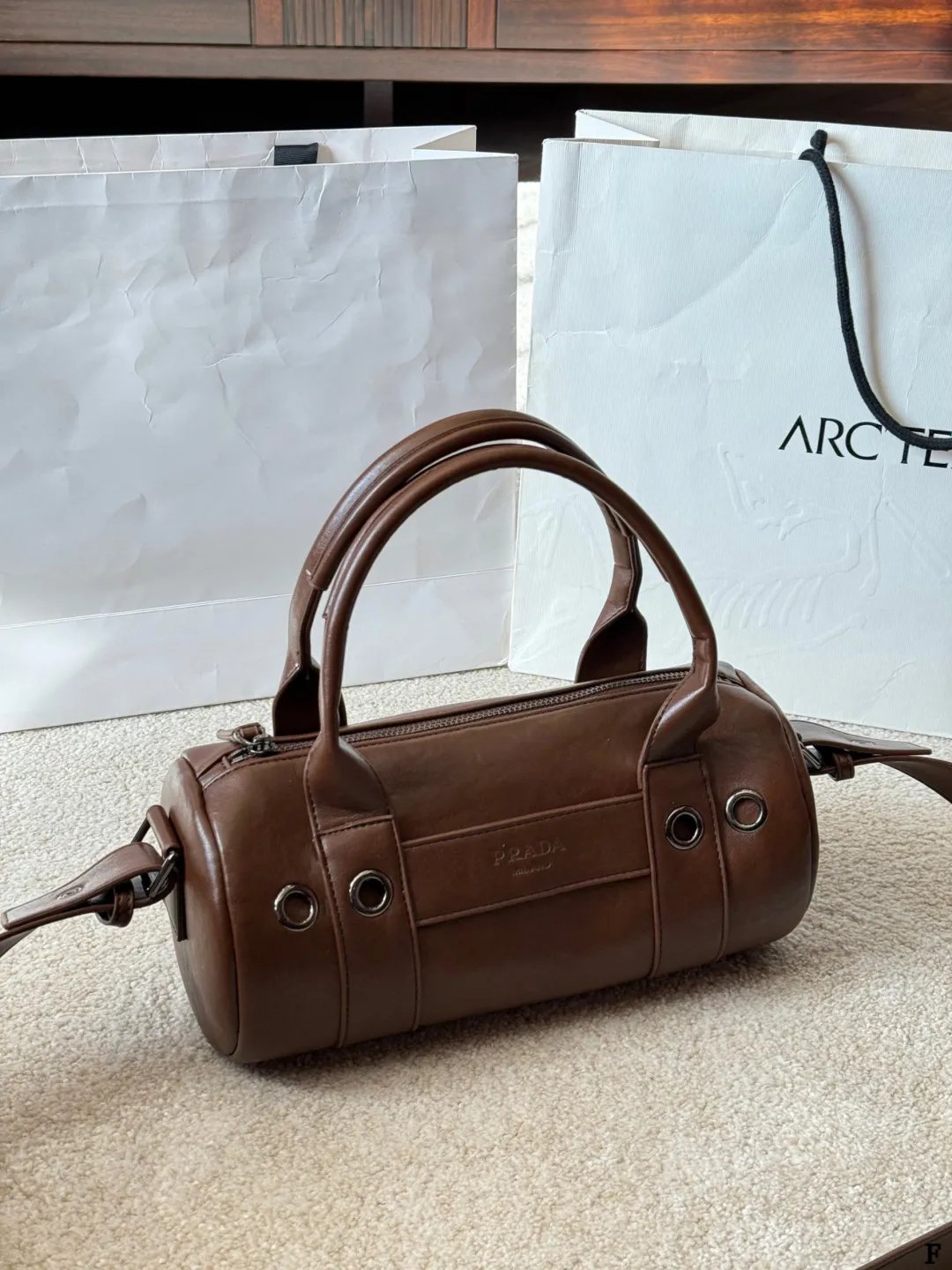 p170 Prada 26SS圆筒包 些Prada 26SS圆筒包是春夏系列新品,棕色皮革质感细腻耐用,简约复古风格超有范!圆筒造型+双提手+可拆卸肩带,手提斜挎都OK,通勤休闲都能搭。正面Logo低调有辨识度,金属环扣点缀细节满分。日本快闪首发,稀缺属性,时尚实用,Prada粉丝必入! 尺寸 30 15cm