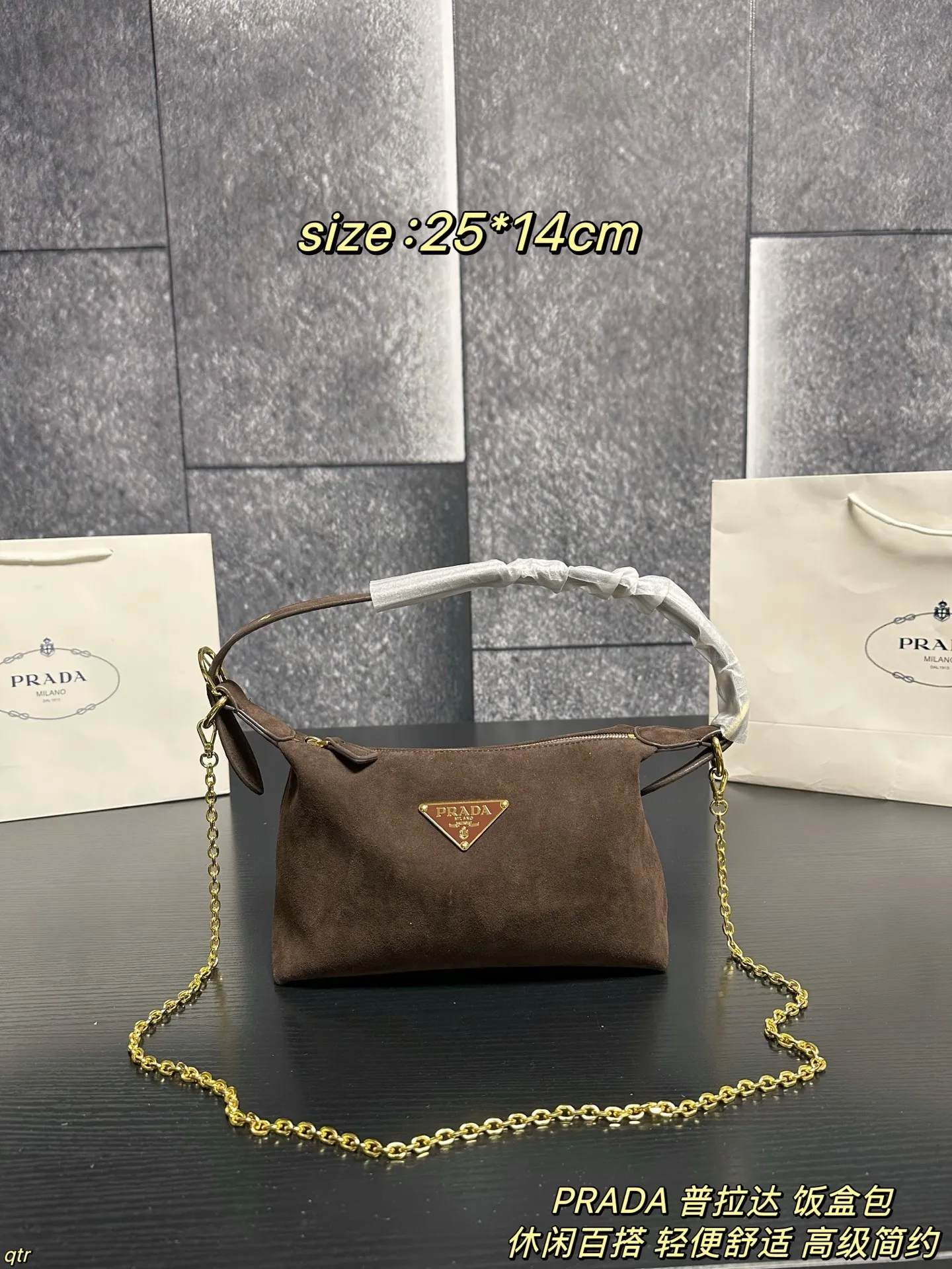 P105配盒 PRADA 普拉达 饭盒包 这款包采用进口麂皮,具有柔软的轮廓和多个口袋,轻质实用的Re-Nylon强调了设计的多功能风格,而皮革细节和标志性点缀则反映了Prada的手工传统,配有2条可拆卸、可调节的编织标志带肩带,容量空间大,上身效果非常时尚。又是一款永久不过时爆款。值得拥有 尺寸:25*14cm