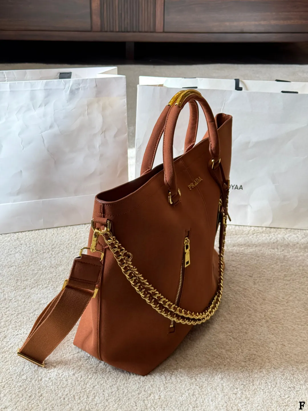 p190 Prada链条托特包 Prada这款棕色链条托特包,采用优质牛皮,手感细腻耐用。金属链条+皮革肩带,手提斜挎都OK,超百搭!正面Logo低调有辦识度,内部空间超大,通勤or短途旅行都能装下日常用品。拉链口袋设计,收纳更方便,实用又时髦,是都市女生的热门选择! 尺寸 35 33cm