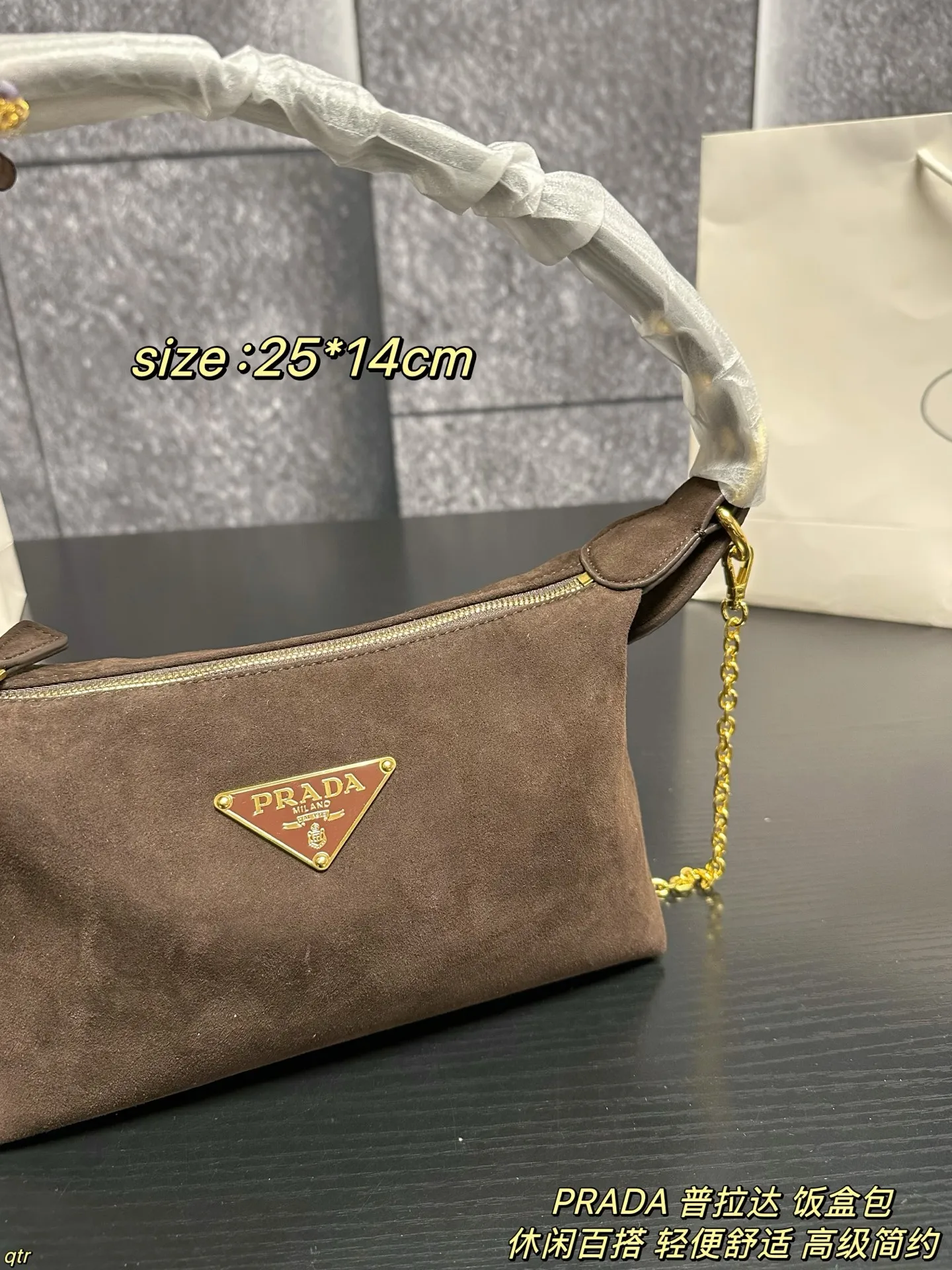 P105配盒 PRADA 普拉达 饭盒包 这款包采用进口麂皮,具有柔软的轮廓和多个口袋,轻质实用的Re-Nylon强调了设计的多功能风格,而皮革细节和标志性点缀则反映了Prada的手工传统,配有2条可拆卸、可调节的编织标志带肩带,容量空间大,上身效果非常时尚。又是一款永久不过时爆款。值得拥有 尺寸:25*14cm