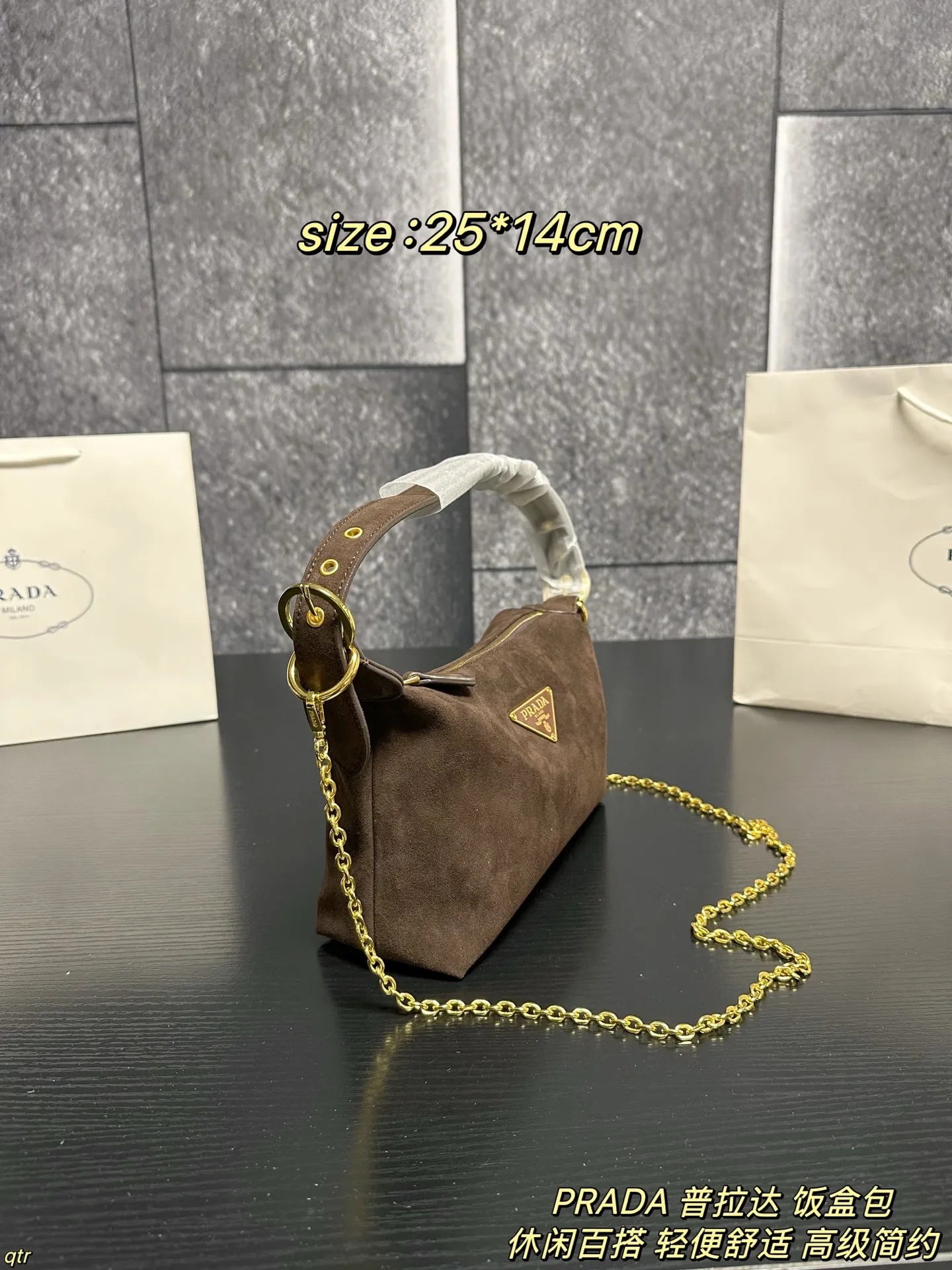 P105配盒 PRADA 普拉达 饭盒包 这款包采用进口麂皮,具有柔软的轮廓和多个口袋,轻质实用的Re-Nylon强调了设计的多功能风格,而皮革细节和标志性点缀则反映了Prada的手工传统,配有2条可拆卸、可调节的编织标志带肩带,容量空间大,上身效果非常时尚。又是一款永久不过时爆款。值得拥有 尺寸:25*14cm
