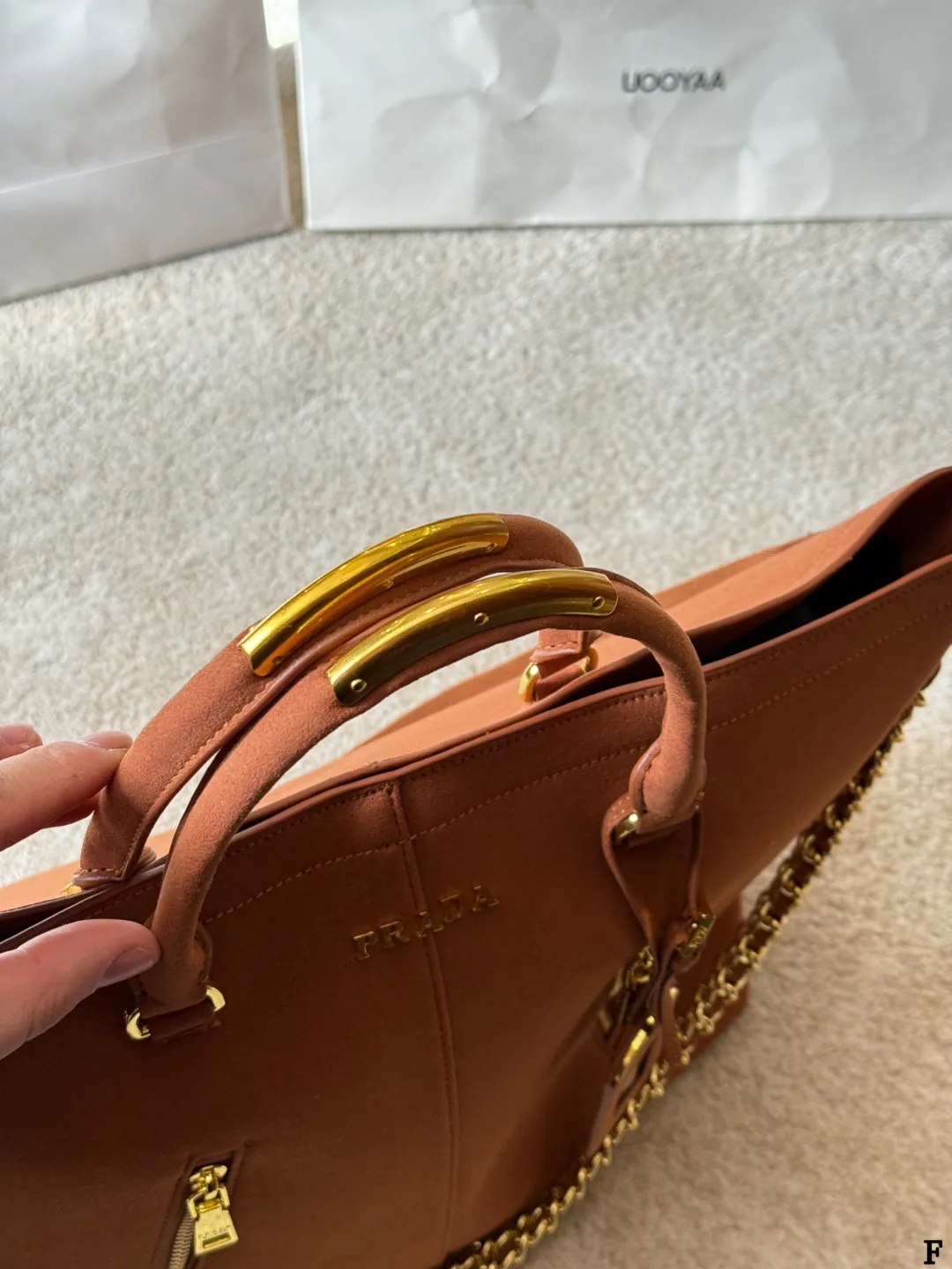 p190 Prada链条托特包 Prada这款棕色链条托特包,采用优质牛皮,手感细腻耐用。金属链条+皮革肩带,手提斜挎都OK,超百搭!正面Logo低调有辦识度,内部空间超大,通勤or短途旅行都能装下日常用品。拉链口袋设计,收纳更方便,实用又时髦,是都市女生的热门选择! 尺寸 35 33cm