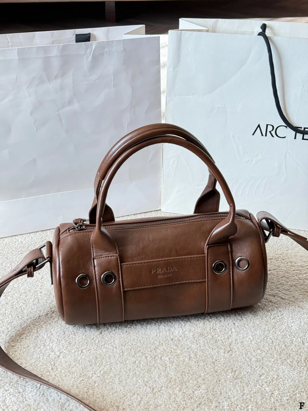 p170 Prada 26SS圆筒包 些Prada 26SS圆筒包是春夏系列新品,棕色皮革质感细腻耐用,简约复古风格超有范!圆筒造型+双提手+可拆卸肩带,手提斜挎都OK,通勤休闲都能搭。正面Logo低调有辨识度,金属环扣点缀细节满分。日本快闪首发,稀缺属性,时尚实用,Prada粉丝必入! 尺寸 30 15cm