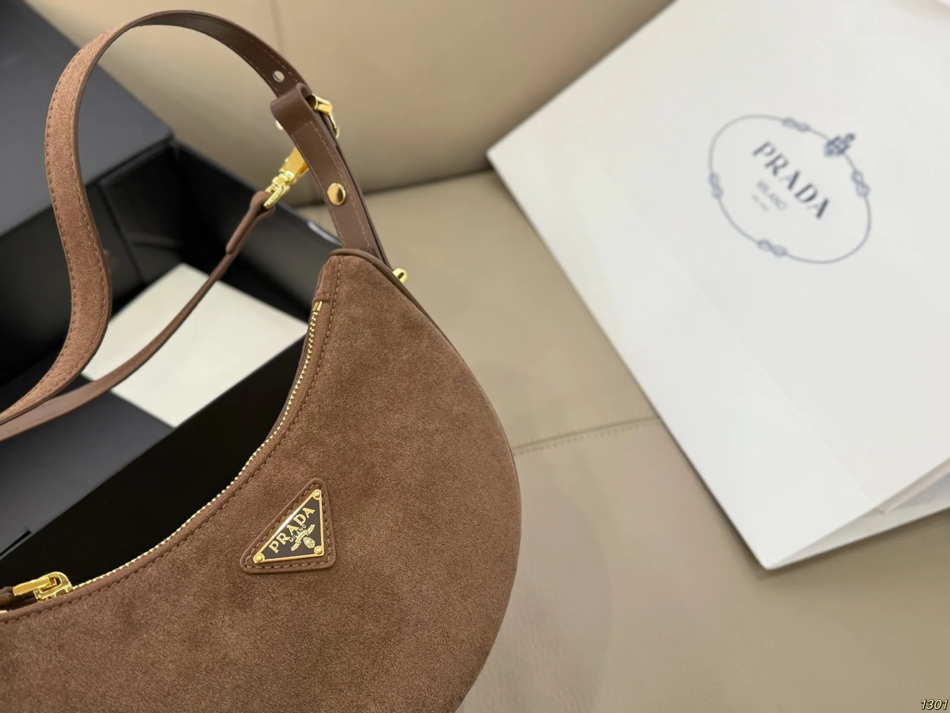 ¥180 Prada 普拉达 Araue麂皮月牙腋下包 弧形乡设计灵感源自新月,皮革+珐琅三角徽标,低调优雅又超有辨识度。双肩带设计,手提肩背都OK,容量适中,通勤休闲都能用。新月造型寓意新生与圆满,实用又时髦,是本季超火单品,明星博主都在背!搭配简约或复古穿搭,气质直接拉满尺寸23*13