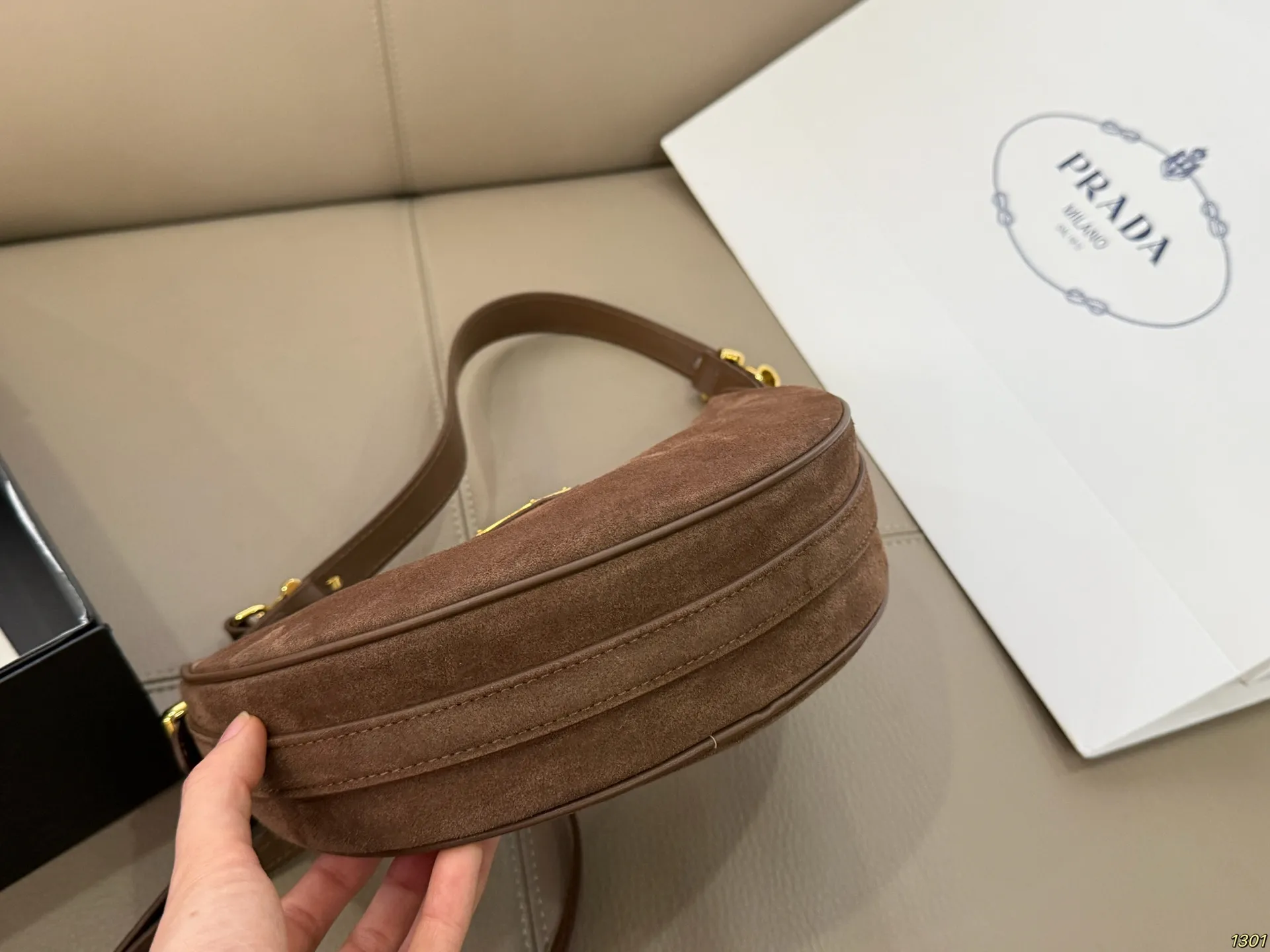 &yen;180 Prada 普拉达 Araue麂皮月牙腋下包 弧形乡设计灵感源自新月，皮革＋珐琅三角徽标，低调优雅又超有辨识度。双肩带设计，手提肩背都OK，容量适中，通勤休闲都能用。新月造型寓意新生与圆满，实用又时髦，是本季超火单品，明星博主都在背！搭配简约或复古穿搭，气质直接拉满尺寸23*13