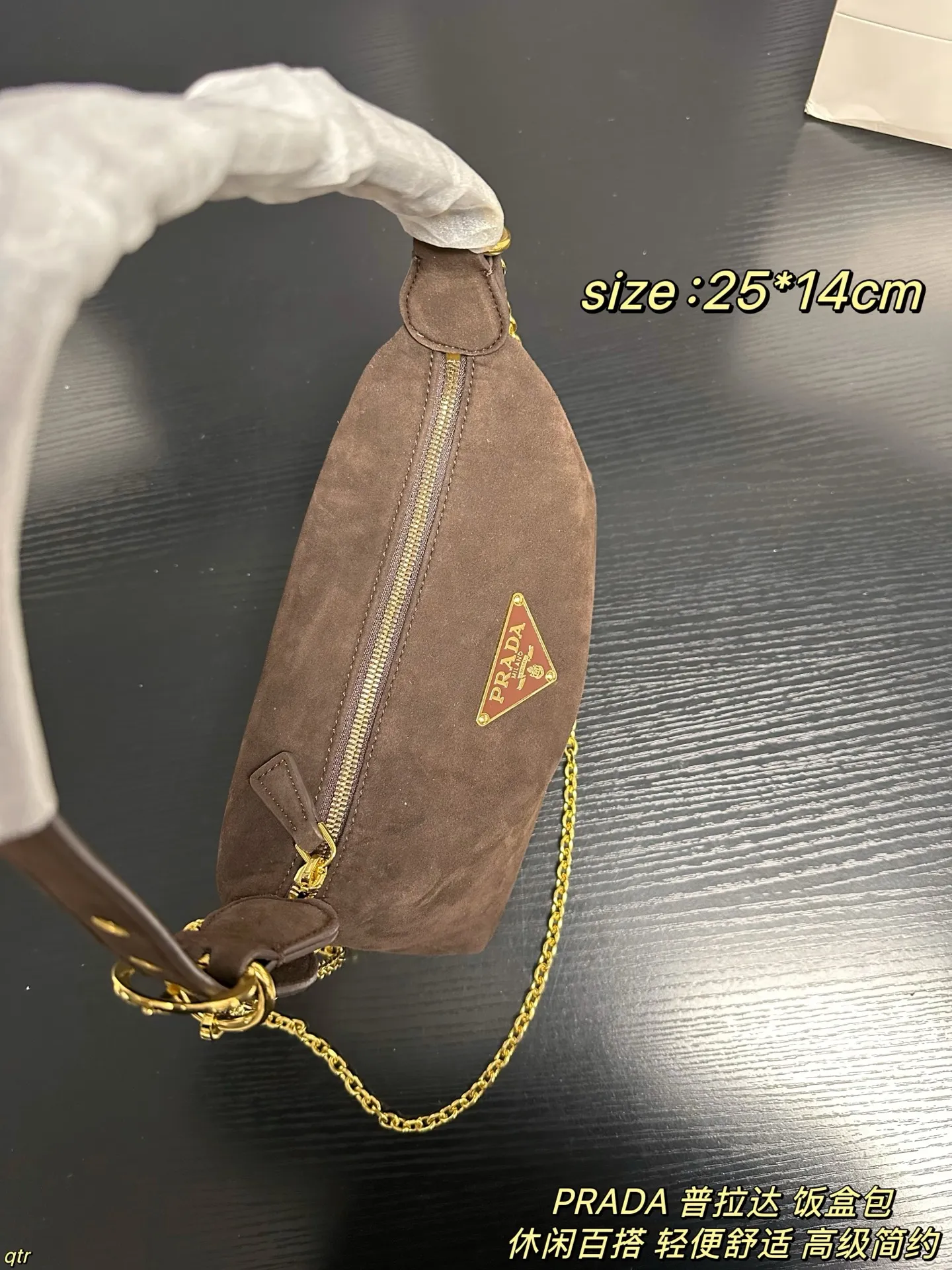 P105配盒 PRADA 普拉达 饭盒包 这款包采用进口麂皮，具有柔软的轮廓和多个口袋，轻质实用的Re-Nylon强调了设计的多功能风格，而皮革细节和标志性点缀则反映了Prada的手工传统，配有2条可拆卸、可调节的编织标志带肩带，容量空间大，上身效果非常时尚。又是一款永久不过时爆款。值得拥有 尺寸：25*14cm