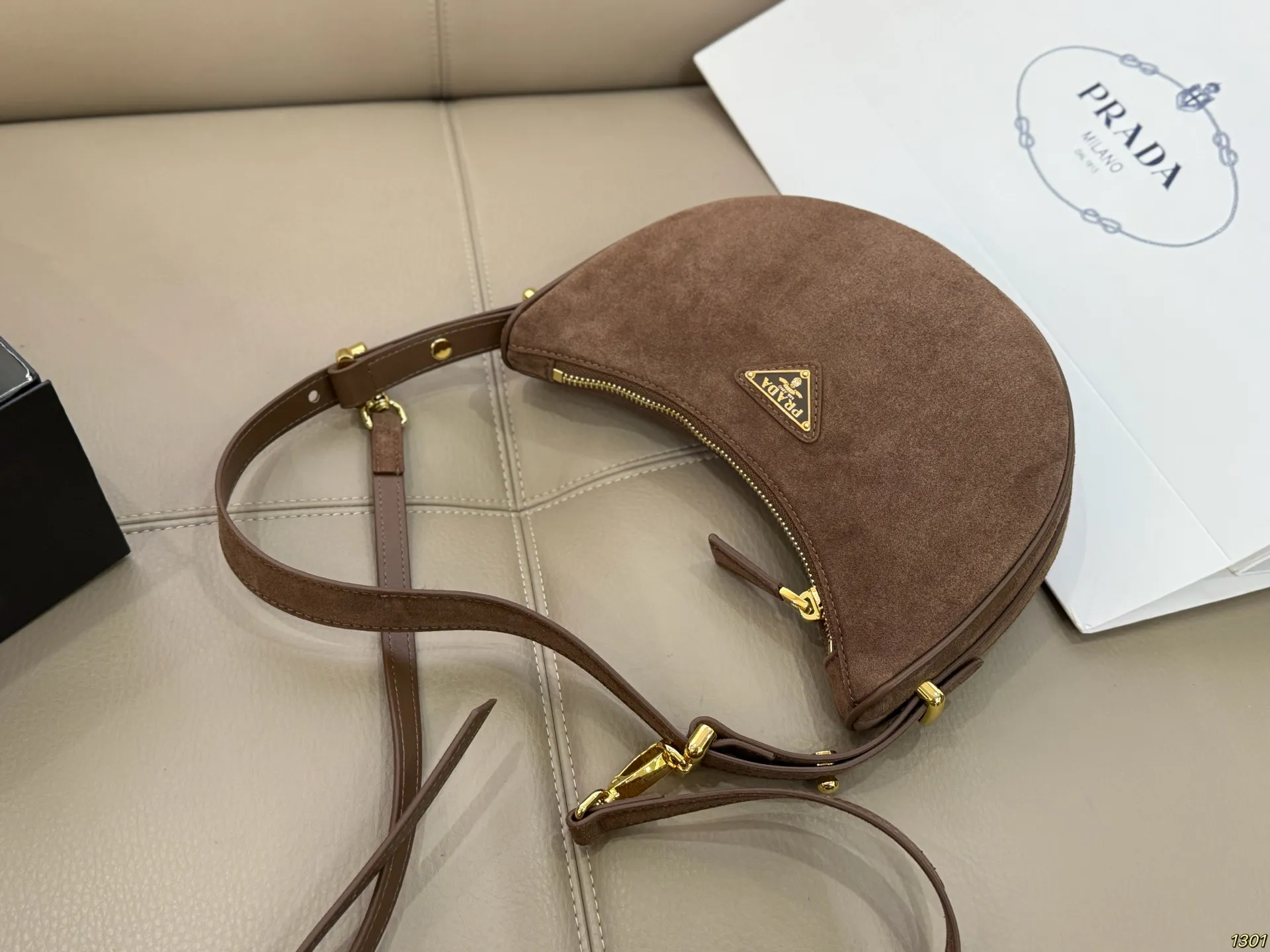 ¥180 Prada 普拉达 Araue麂皮月牙腋下包 弧形乡设计灵感源自新月,皮革+珐琅三角徽标,低调优雅又超有辨识度。双肩带设计,手提肩背都OK,容量适中,通勤休闲都能用。新月造型寓意新生与圆满,实用又时髦,是本季超火单品,明星博主都在背!搭配简约或复古穿搭,气质直接拉满尺寸23*13