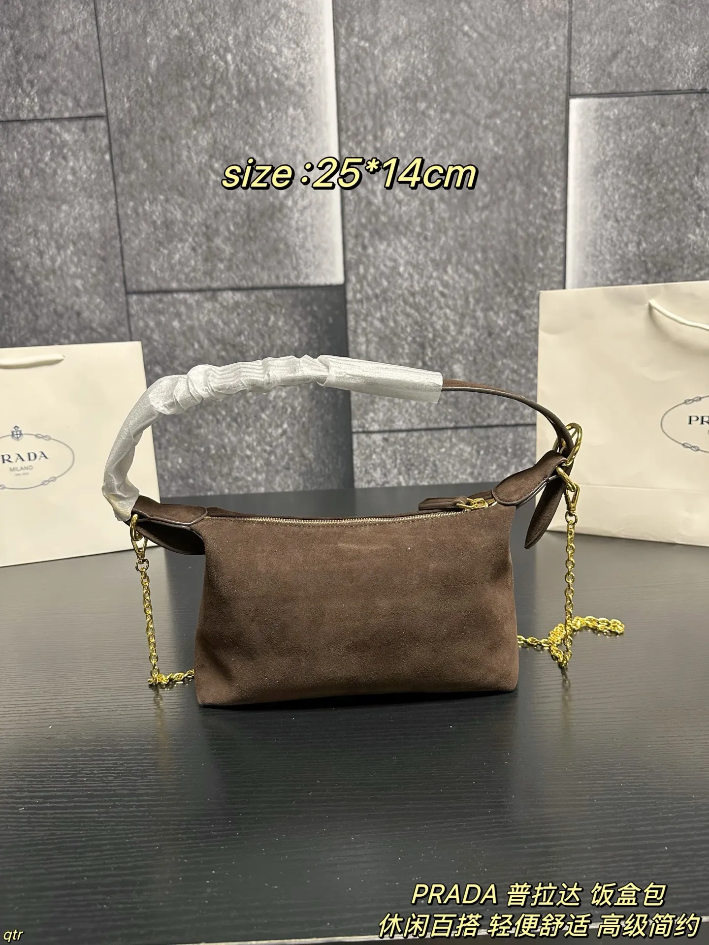 P105配盒 PRADA 普拉达 饭盒包 这款包采用进口麂皮,具有柔软的轮廓和多个口袋,轻质实用的Re-Nylon强调了设计的多功能风格,而皮革细节和标志性点缀则反映了Prada的手工传统,配有2条可拆卸、可调节的编织标志带肩带,容量空间大,上身效果非常时尚。又是一款永久不过时爆款。值得拥有 尺寸:25*14cm