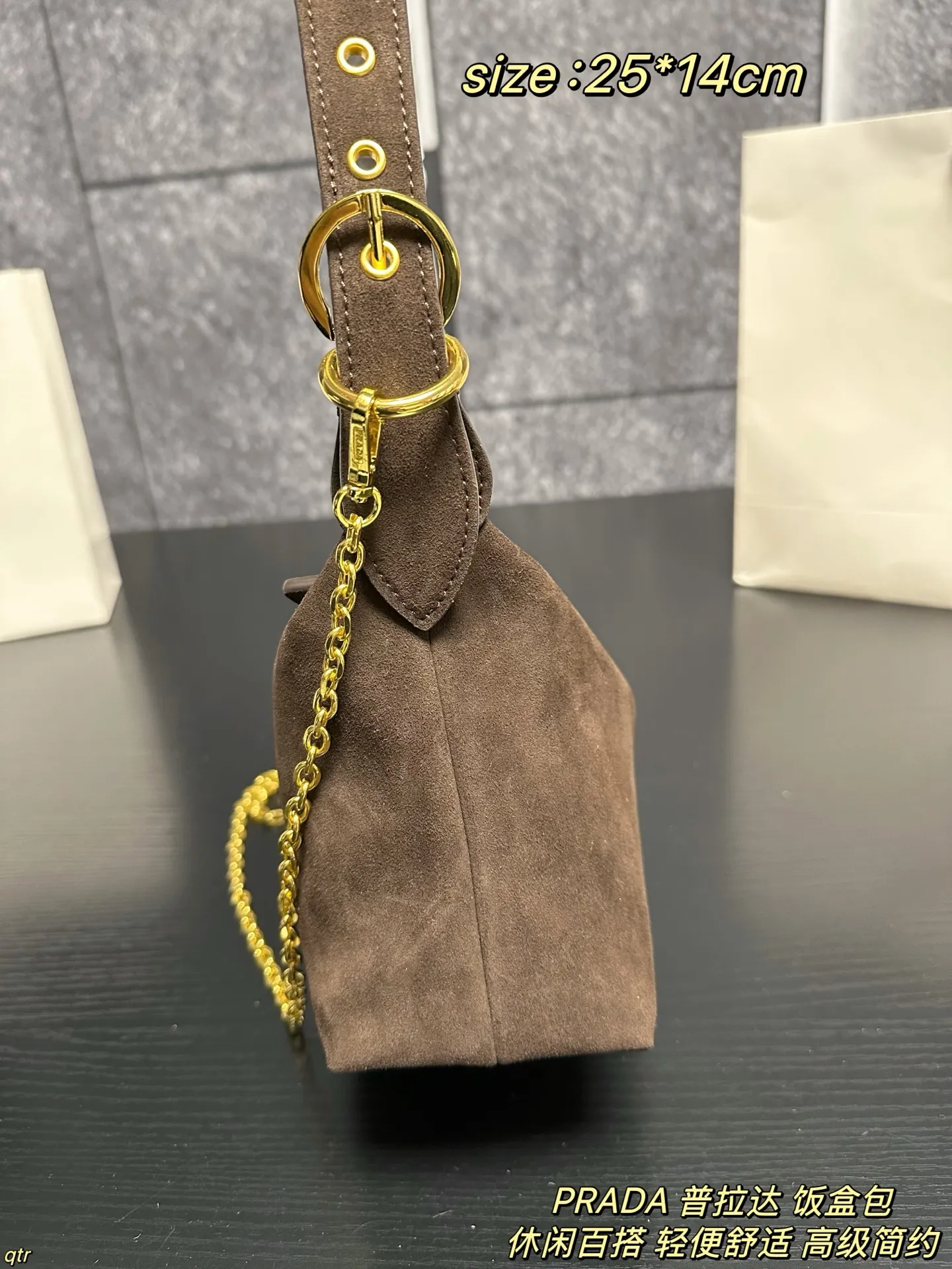 P105配盒 PRADA 普拉达 饭盒包 这款包采用进口麂皮，具有柔软的轮廓和多个口袋，轻质实用的Re-Nylon强调了设计的多功能风格，而皮革细节和标志性点缀则反映了Prada的手工传统，配有2条可拆卸、可调节的编织标志带肩带，容量空间大，上身效果非常时尚。又是一款永久不过时爆款。值得拥有 尺寸：25*14cm