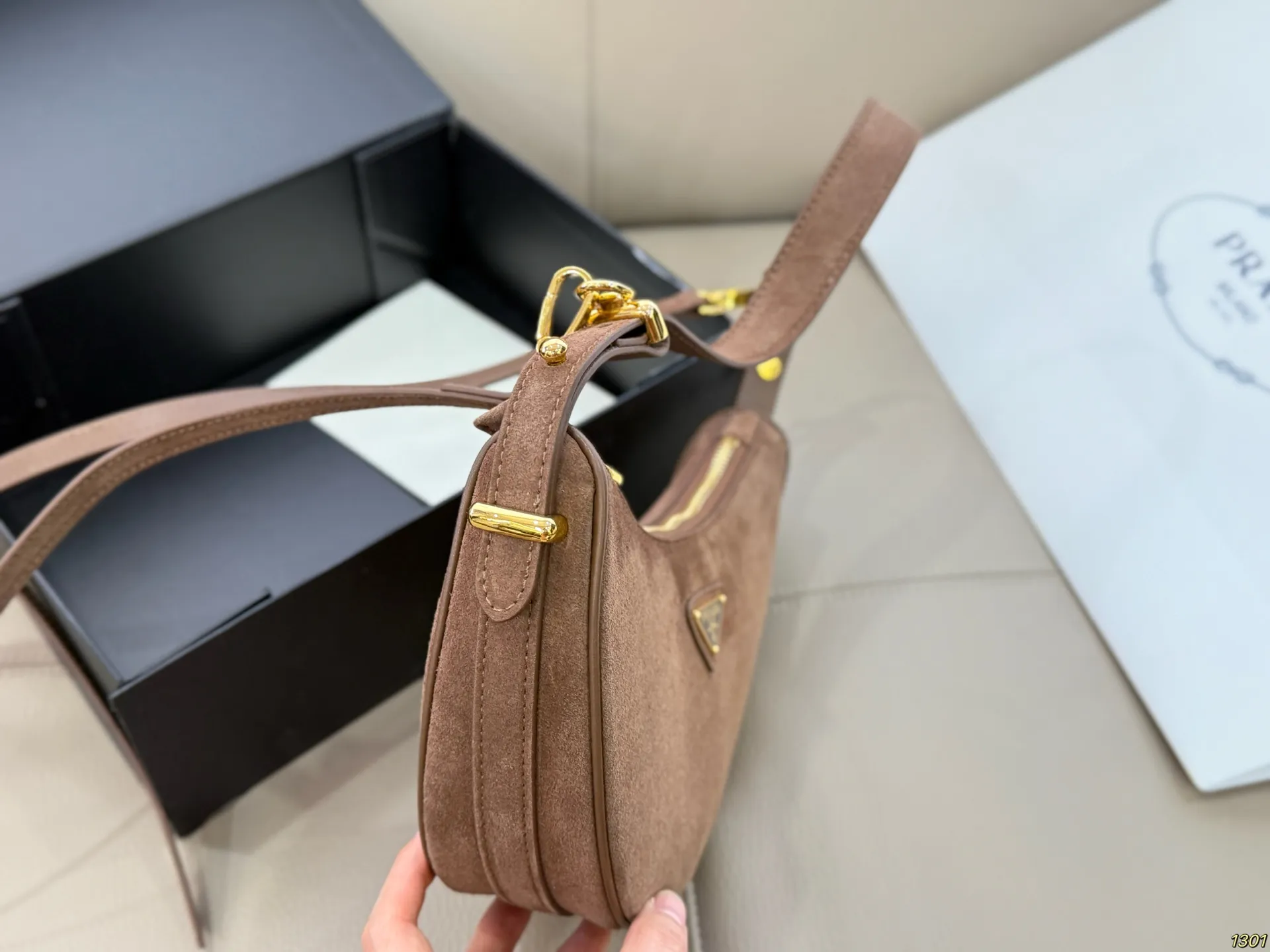 &yen;180 Prada 普拉达 Araue麂皮月牙腋下包 弧形乡设计灵感源自新月，皮革＋珐琅三角徽标，低调优雅又超有辨识度。双肩带设计，手提肩背都OK，容量适中，通勤休闲都能用。新月造型寓意新生与圆满，实用又时髦，是本季超火单品，明星博主都在背！搭配简约或复古穿搭，气质直接拉满尺寸23*13