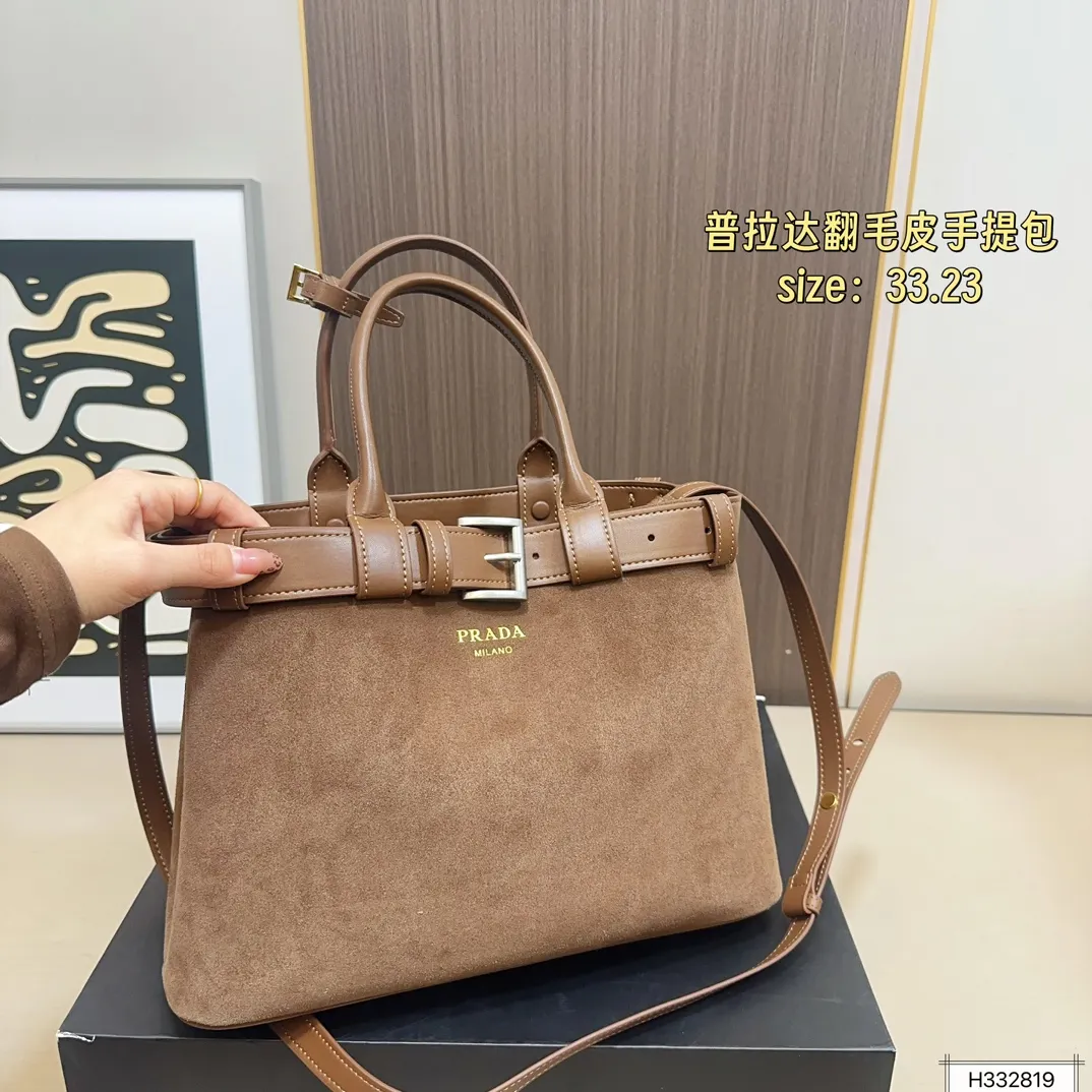 💰235 配盒⚠️尺寸33*23 Prada 普拉达 Buckle翻毛皮手提包 2024春夏系列，采用柔软麂皮，触感细腻，低调哑光质感超有氛围感。标志性金属腰带＋三角徽标，辨识度满分！尺寸适中中，通勤休闲都能轻松驾驱。肩带可拆卸调节，手提斜挎随心切换，实用又时髦。简约大气，时尚爱好者必入！