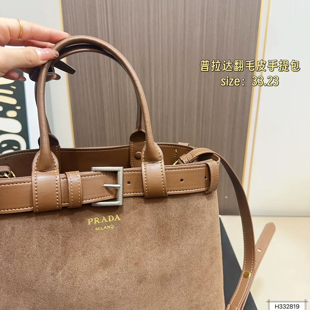 💰235 配盒⚠️尺寸33*23 Prada 普拉达 Buckle翻毛皮手提包 2024春夏系列，采用柔软麂皮，触感细腻，低调哑光质感超有氛围感。标志性金属腰带＋三角徽标，辨识度满分！尺寸适中中，通勤休闲都能轻松驾驱。肩带可拆卸调节，手提斜挎随心切换，实用又时髦。简约大气，时尚爱好者必入！