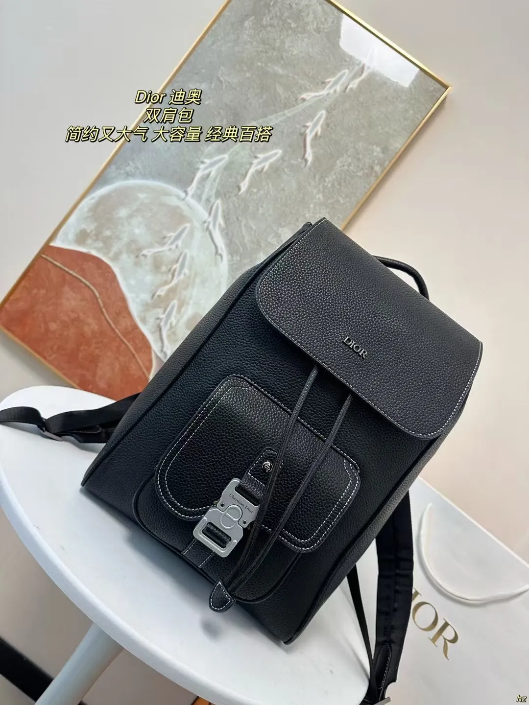 P185 Dior 迪奥 双肩包 这款马鞍双肩背包是二零二四秋季男装系列新品，采用时尚的原创设计，突显马鞍风格。黑色粒面牛皮革搭配对比鲜明的缉面线，正面饰以Dior标志。空间宽敞，设有一个隔层,可收纳各种日常用品，正面马鞍翻盖，可收纳钱包、钥匙、耳机或手机,便于轻松取用。实用百搭，是各式造型的点睛之笔。 尺寸：28*42CM