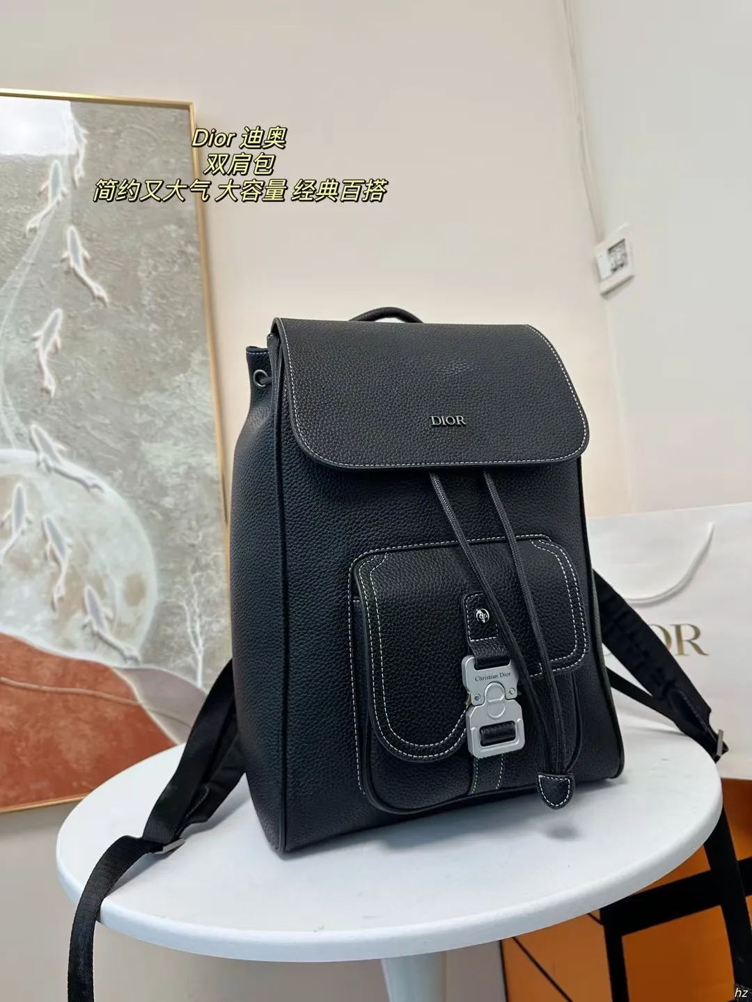 P185 Dior 迪奥 双肩包 这款马鞍双肩背包是二零二四秋季男装系列新品，采用时尚的原创设计，突显马鞍风格。黑色粒面牛皮革搭配对比鲜明的缉面线，正面饰以Dior标志。空间宽敞，设有一个隔层,可收纳各种日常用品，正面马鞍翻盖，可收纳钱包、钥匙、耳机或手机,便于轻松取用。实用百搭，是各式造型的点睛之笔。 尺寸：28*42CM