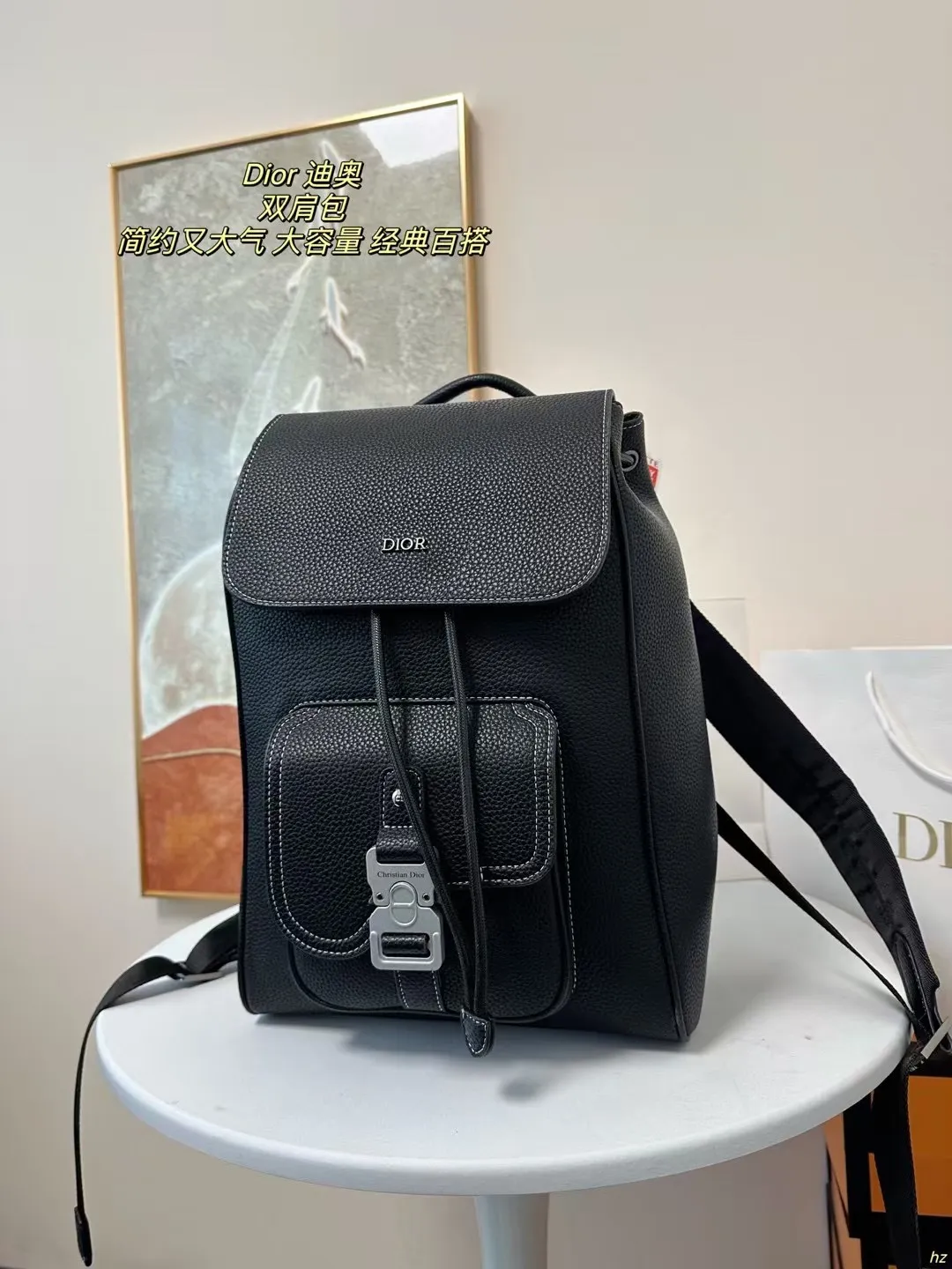 P185 Dior 迪奥 双肩包 这款马鞍双肩背包是二零二四秋季男装系列新品，采用时尚的原创设计，突显马鞍风格。黑色粒面牛皮革搭配对比鲜明的缉面线，正面饰以Dior标志。空间宽敞，设有一个隔层,可收纳各种日常用品，正面马鞍翻盖，可收纳钱包、钥匙、耳机或手机,便于轻松取用。实用百搭，是各式造型的点睛之笔。 尺寸：28*42CM