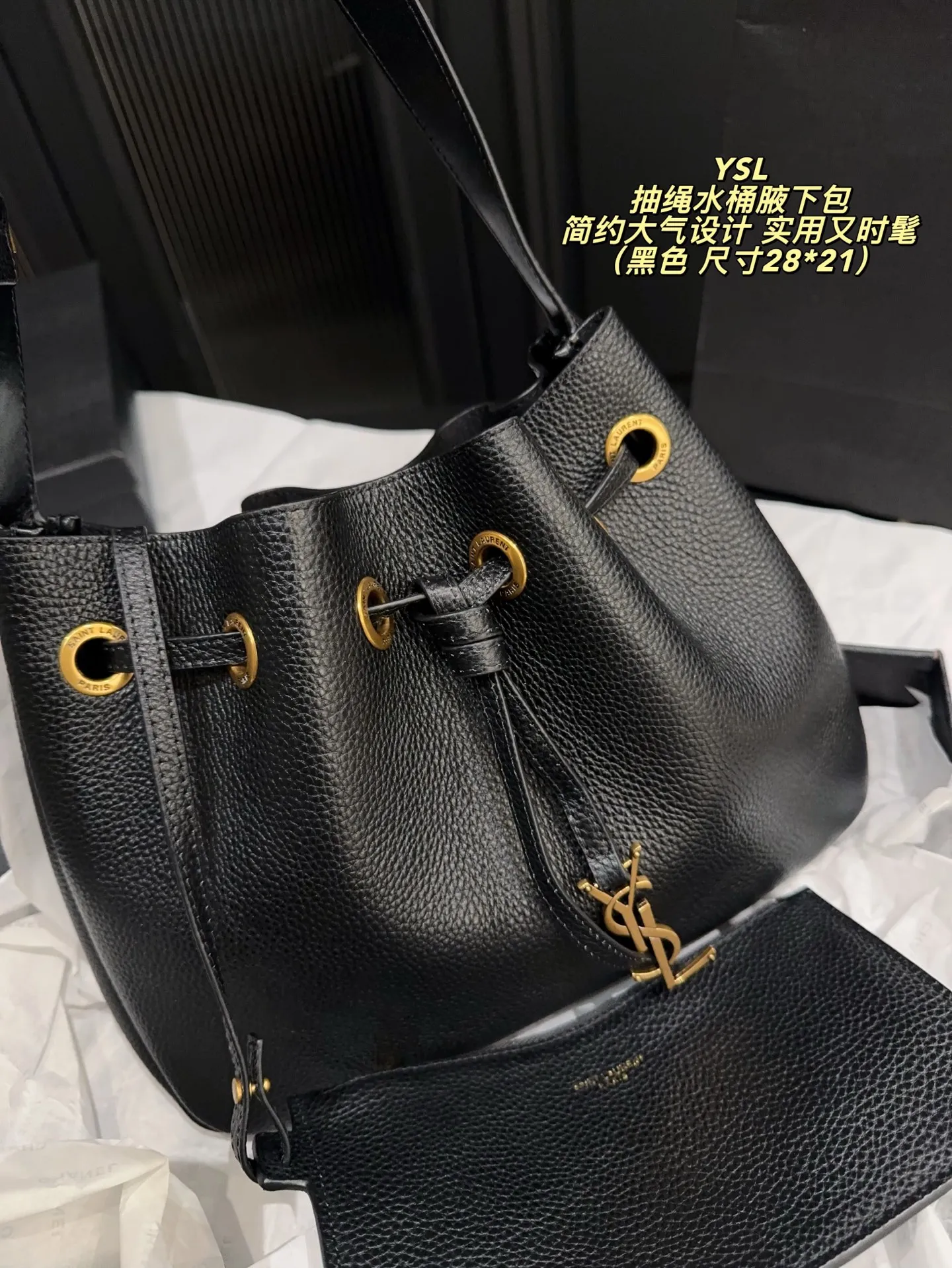 P200配折叠盒⚠️尺寸28*21 圣罗兰 YSL 抽绳水桶腋下包 黑色荔枝纹牛皮，质感细腻耐用，金属抽绳十YSL标志超有辨识度。尺寸适中，通勤休闲都能用，手提斜挎随心切换，内部空问合理，日常物品轻松收纳。简约大气设计，百搭不挑风格，秋冬深色系穿搭必备，实用又时髦！