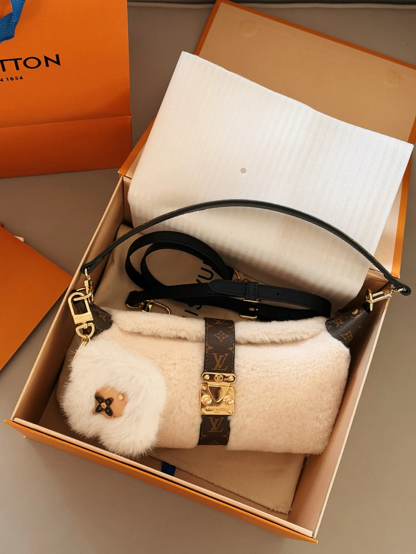 💰 180配盒 赠送挂件哦! size:21.5*12cm L家 新款MIA饺子包 小小饭盒包拿捏 奶呼呼的毛绒包 摸起来像抱着一团云朵, 老花皮拼接+金属扣设计复古又高级 还有可爱的花朵挂饰加持 冬天背它出门,保暖又吸睛哦!