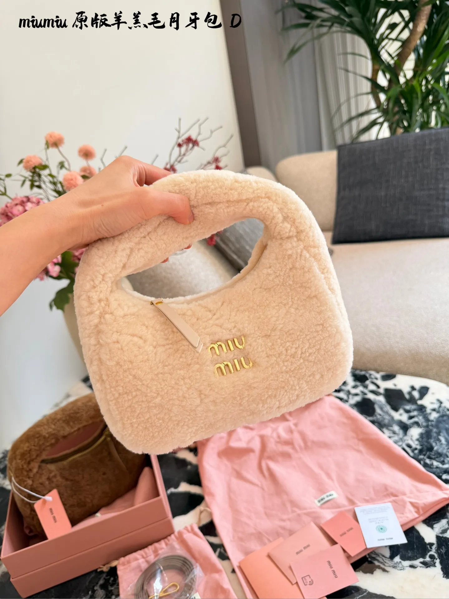 p255 Miu Miu羊羔毛Mini Wander手提包 &这款Miu Miu羊羔毛Mini Wander手提包,采用柔软羊 羔毛,触感超温暖,秋冬必备!奶茶色包身+金色L ogo刺绣,精致又有辨识度十。尺寸小巧,手提or肩背都OK,配有链条和肩带,百搭各种穿搭风格。内部空间刚好,手机、钥匙轻松收纳,实用又时髦。23cm配盒子