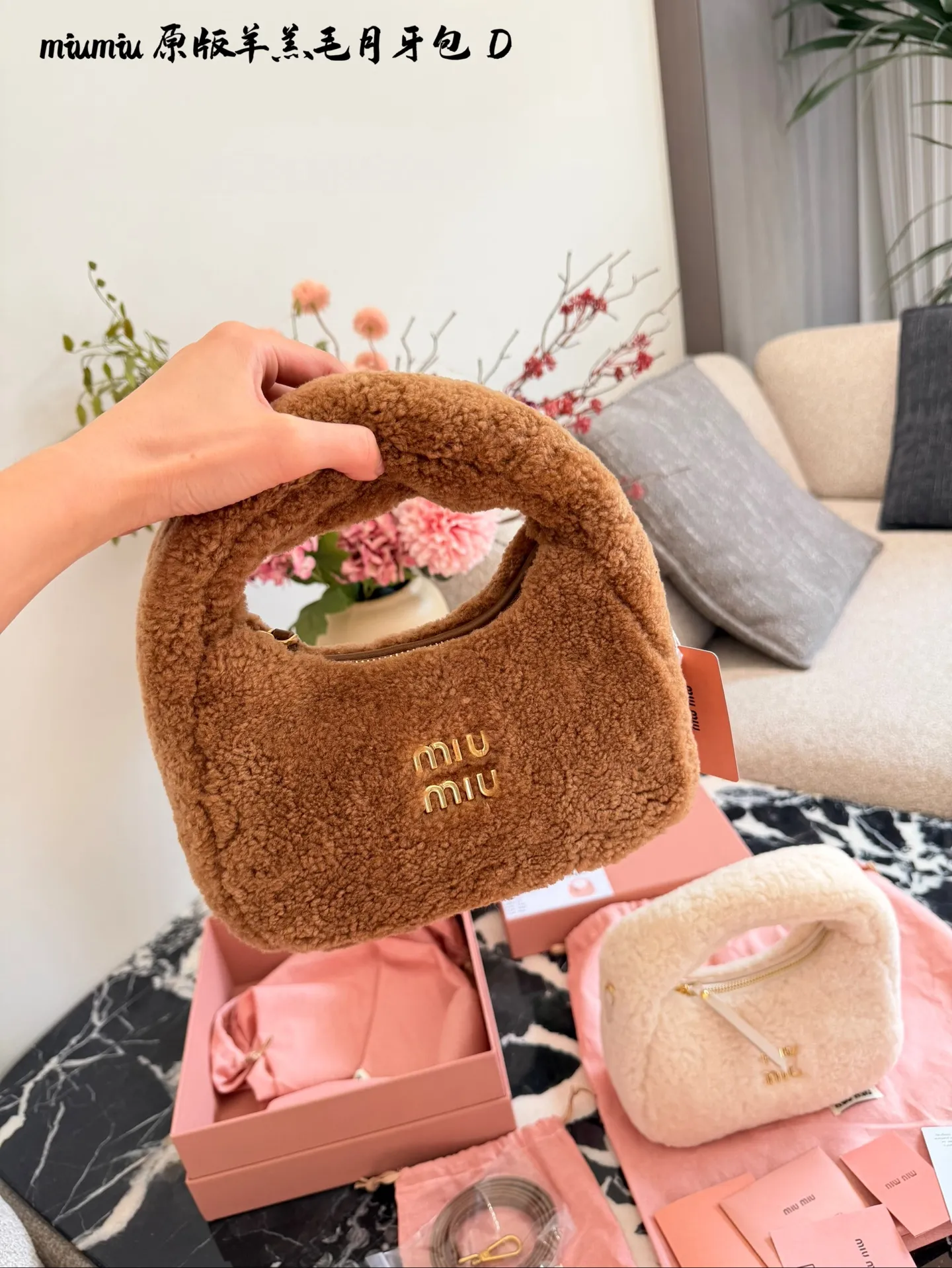 p255 Miu Miu羊羔毛Mini Wander手提包 &这款Miu Miu羊羔毛Mini Wander手提包，采用柔软羊 羔毛，触感超温暖,秋冬必备!奶茶色包身+金色L ogo刺绣，精致又有辨识度十。尺寸小巧，手提or肩背都OK,配有链条和肩带，百搭各种穿搭风格。内部空间刚好，手机、钥匙轻松收纳，实用又时髦。23cm配盒子