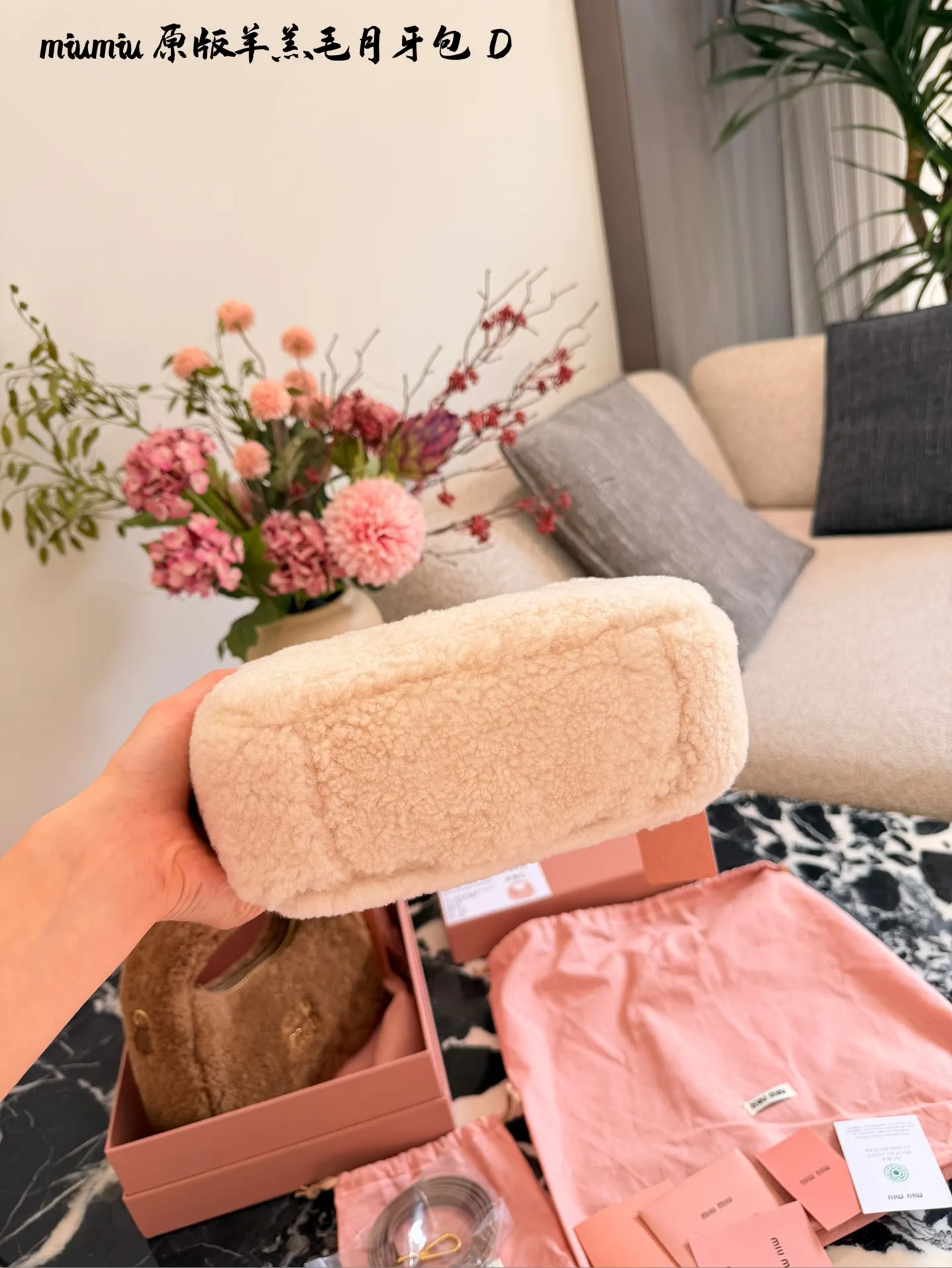 p255 Miu Miu羊羔毛Mini Wander手提包 &这款Miu Miu羊羔毛Mini Wander手提包，采用柔软羊 羔毛，触感超温暖,秋冬必备!奶茶色包身+金色L ogo刺绣，精致又有辨识度十。尺寸小巧，手提or肩背都OK,配有链条和肩带，百搭各种穿搭风格。内部空间刚好，手机、钥匙轻松收纳，实用又时髦。23cm配盒子