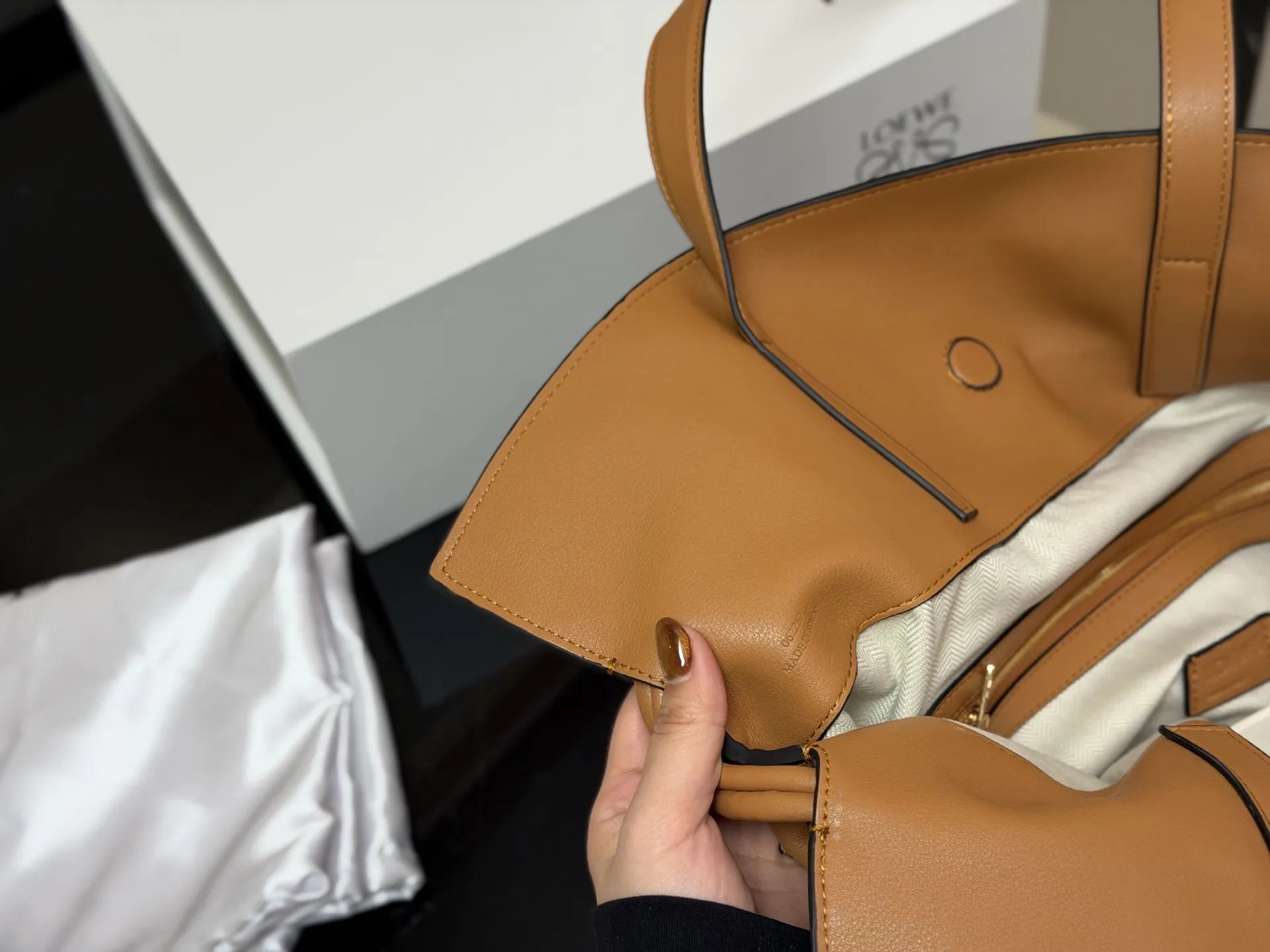 ¥300 配折叠盒 LOEWE 罗意威Anagram福袋托特包 采用柔软纳帕牛皮,手感细腻,廓形随性慵懒。灵感源自日本福袋,抽绳设计方便开合,容量超大,通勤日常都很实用。肩带可调节,支持单肩或斜挎,搭配Anagram印花,低调又有辨识度,时髦精们必入! 尺寸:37.29cm