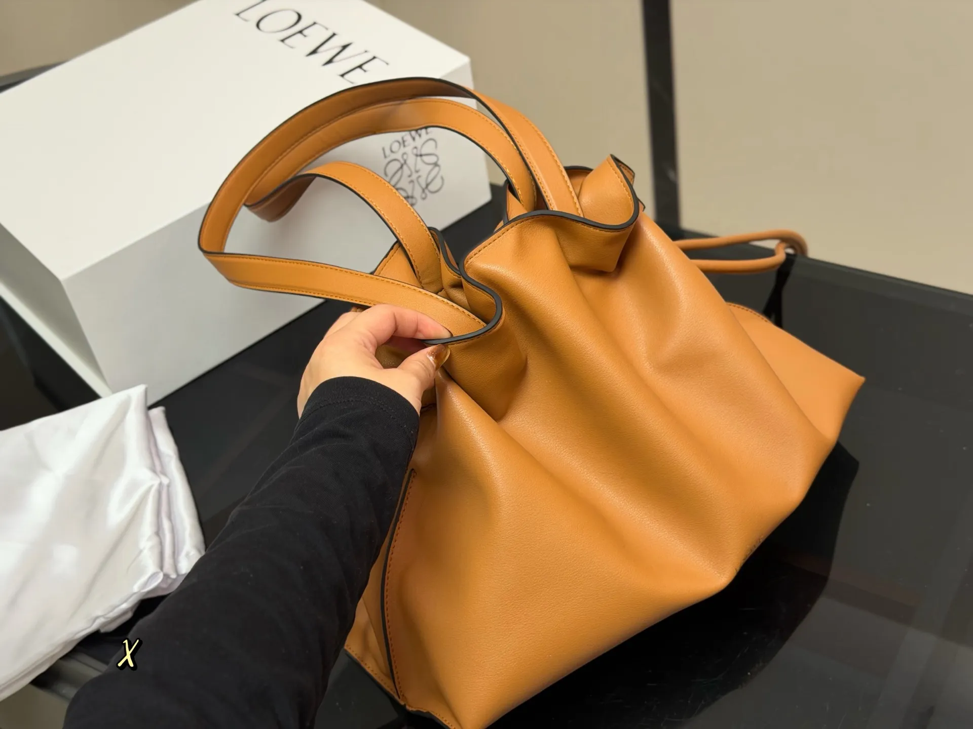 &yen;300 配折叠盒 LOEWE 罗意威Anagram福袋托特包 采用柔软纳帕牛皮，手感细腻，廓形随性慵懒。灵感源自日本福袋，抽绳设计方便开合，容量超大，通勤日常都很实用。肩带可调节，支持单肩或斜挎，搭配Anagram印花，低调又有辨识度，时髦精们必入！ 尺寸:37.29cm