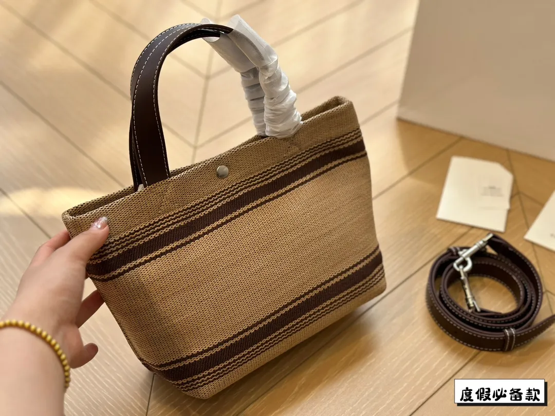 ¥220 Celine新款编织托特包 Celine新款编织包是一款设计简洁而又不失时尚感的托特包。其最显著的特点在于采用了棕色粗细不均条纹的帆布材质,这种设计不仅赋予了包包独特的视觉冲击力,也展现了Celine品牌一贯的优雅与精致。在包的正面醒目地印有大写的“CELINE”字样,既凸显了品牌的身份,也提升了包包的整体美感。20*17